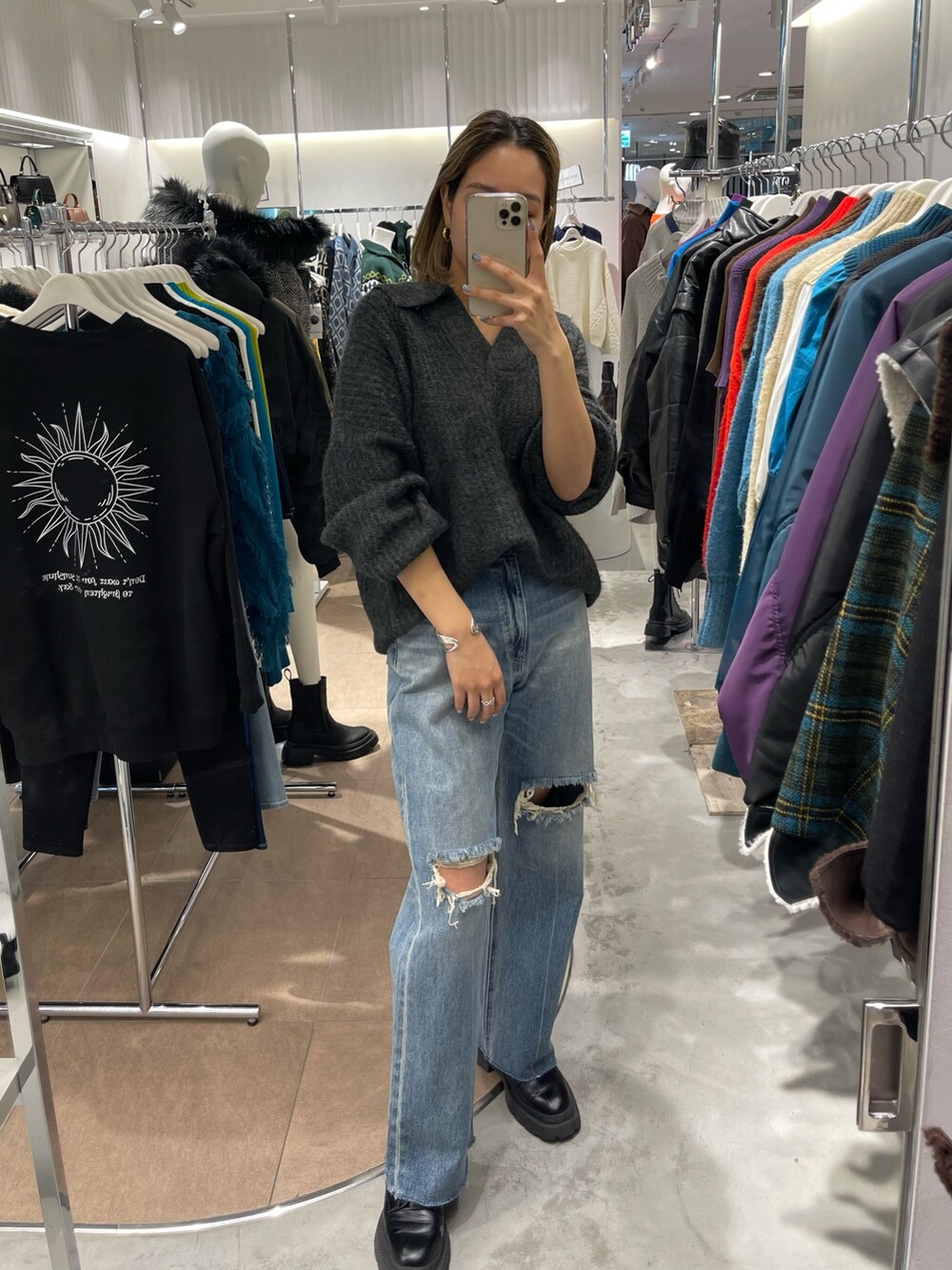 グレー系のニット/セーター、ブラック系のブーツ、ブルー系のデニムパンツを着用したレディースの秋コーディネートの2枚目の写真