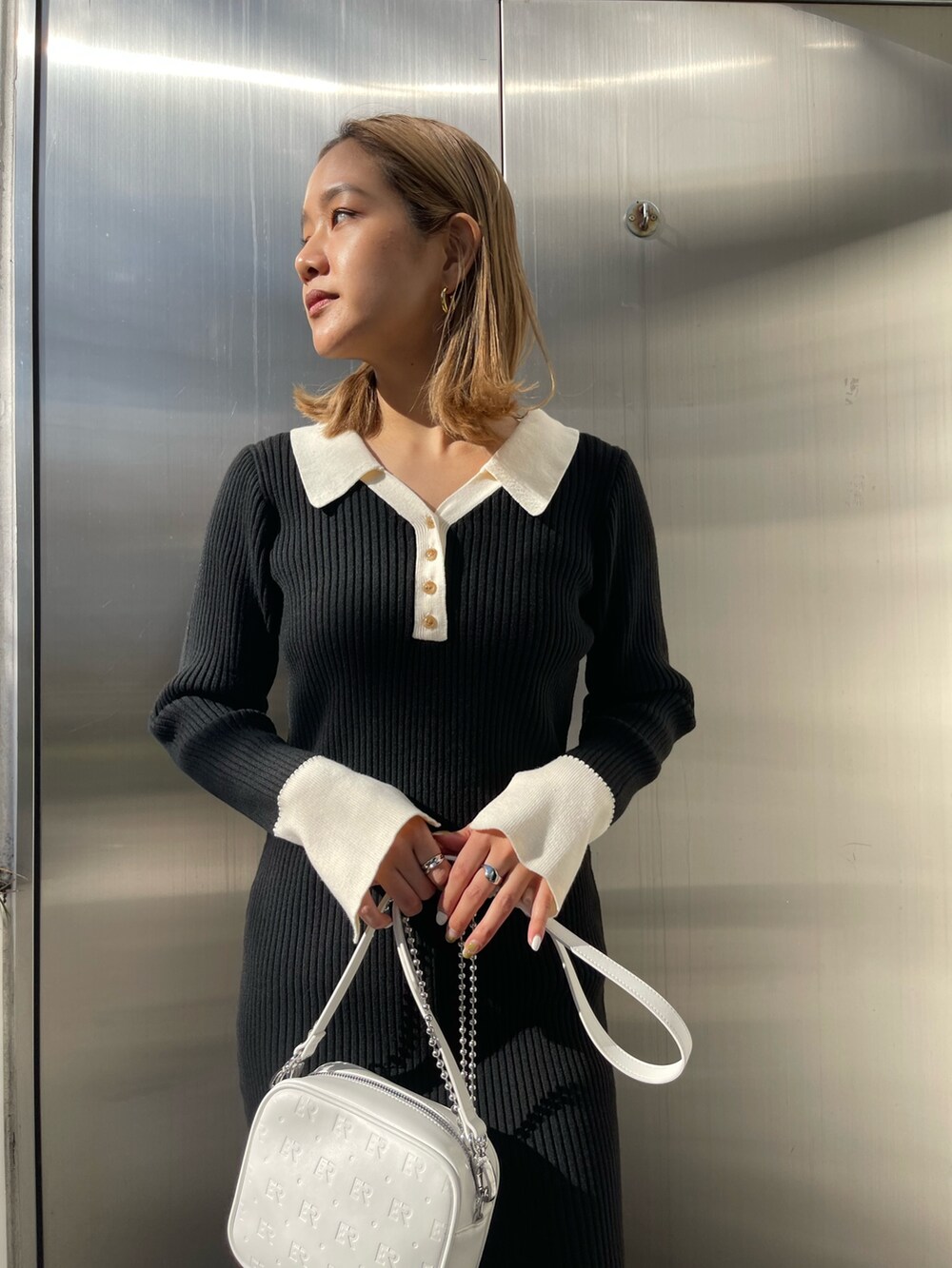 ブラック系のブーツ、ブラック系のワンピース、ホワイト系のショルダーバッグを着用したレディースの冬コーディネートの6枚目の写真