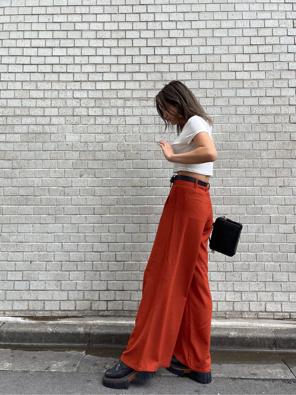 ブラック系のローファー、オレンジ系のその他パンツ、ブラック系のハンドバッグを着用したレディースの夏コーディネートの2枚目の写真