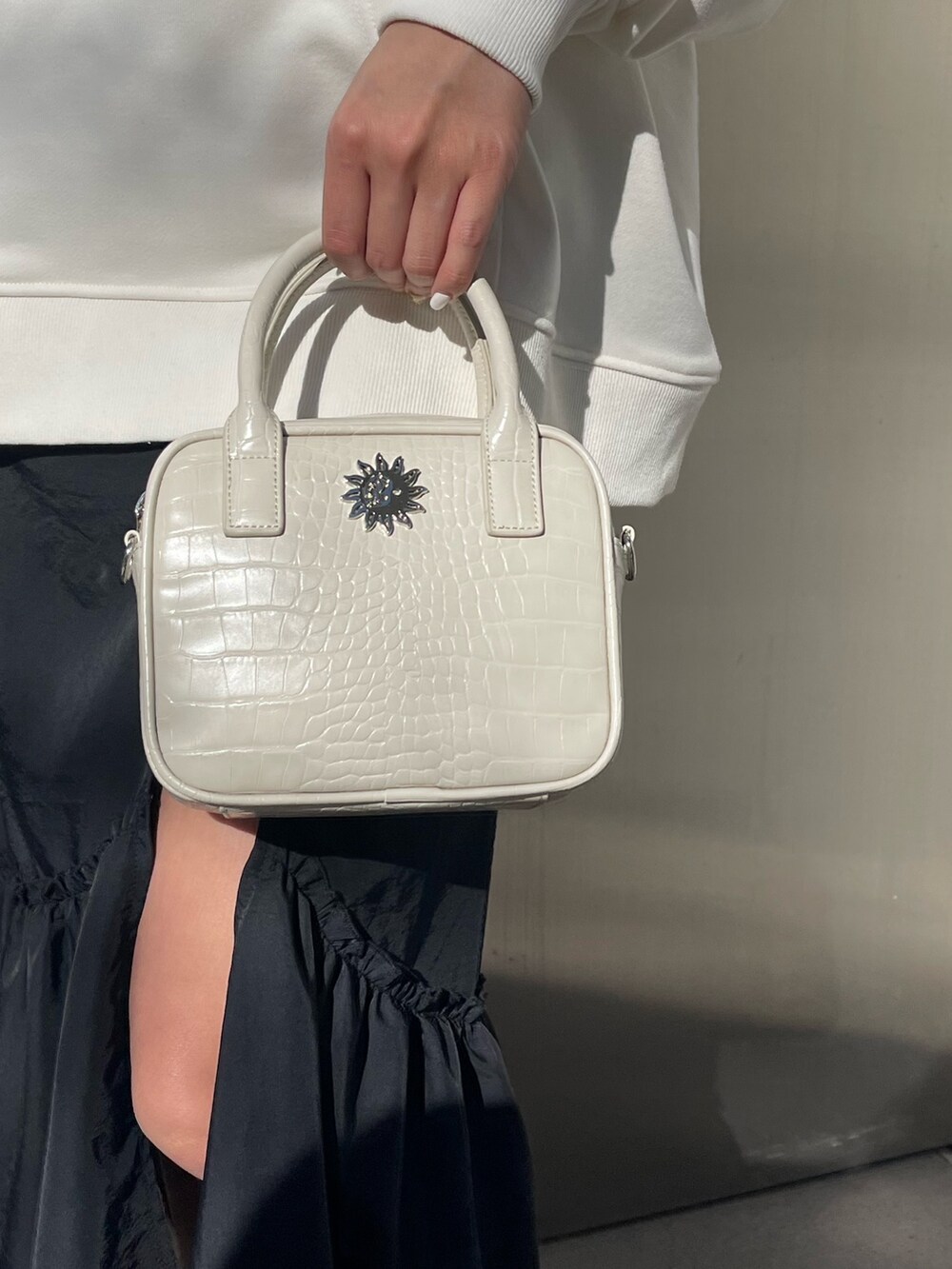 ブラック系のワンピース、ホワイト系のショルダーバッグ、ブラック系のブーツを着用したレディースの冬コーディネートの6枚目の写真