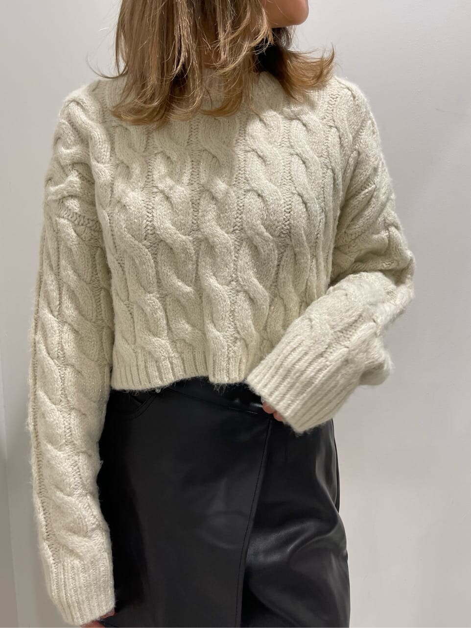 ブラック系のブーツ、ブラック系のスカート、ホワイト系のニット/セーターを着用したレディースの秋コーディネートの5枚目の写真