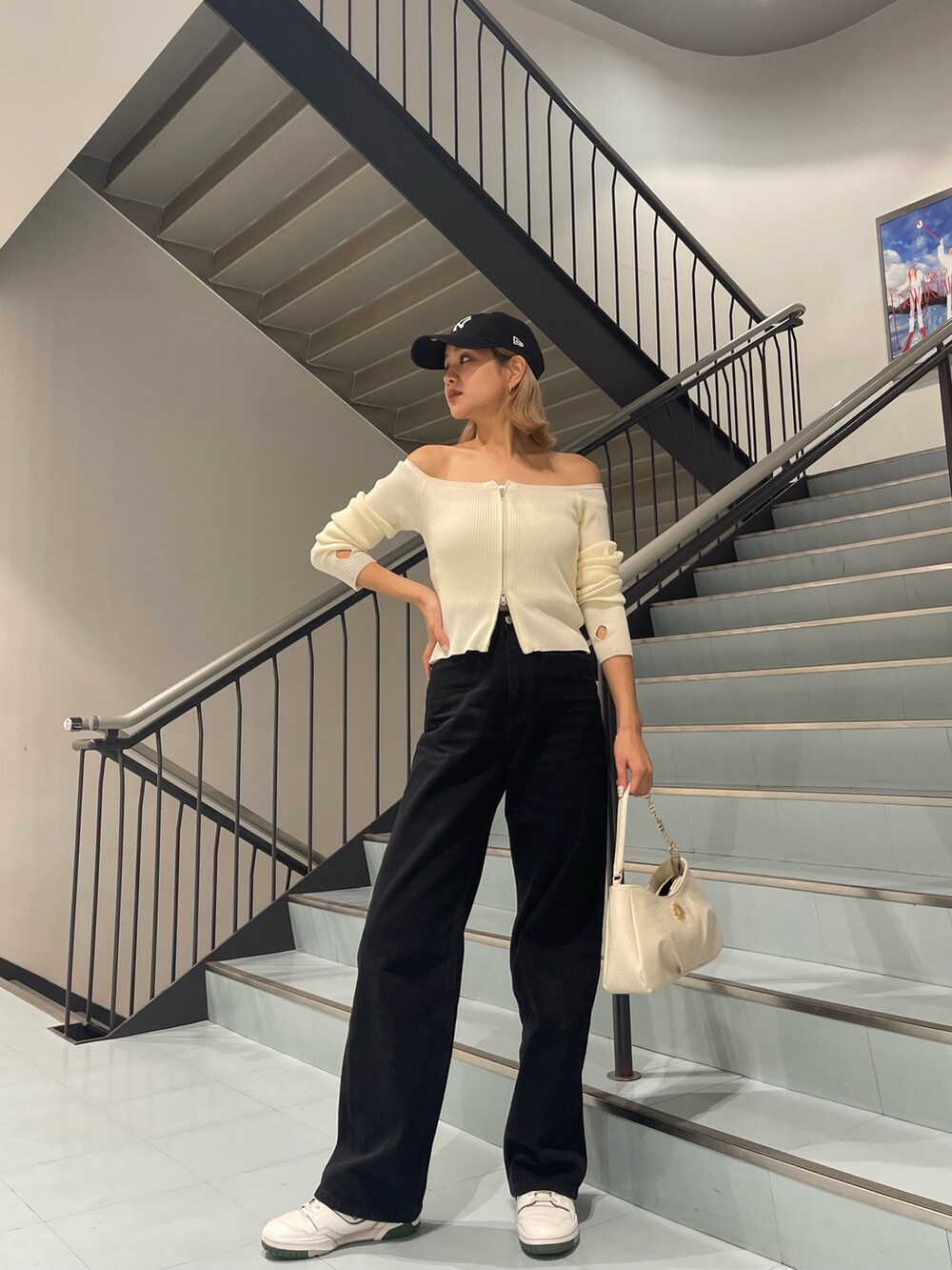 ホワイト系のニット/セーター、ブラック系のデニムパンツ、ホワイト系のハンドバッグを着用したレディースの夏コーディネートの3枚目の写真