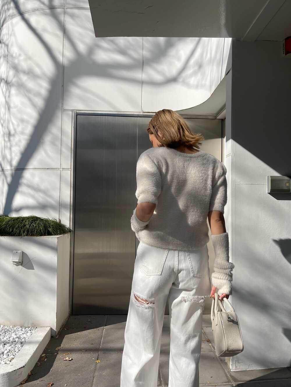 ホワイト系のショルダーバッグ、ホワイト系のサンダル、ホワイト系のニット/セーターを着用したレディースの冬コーディネートの5枚目の写真