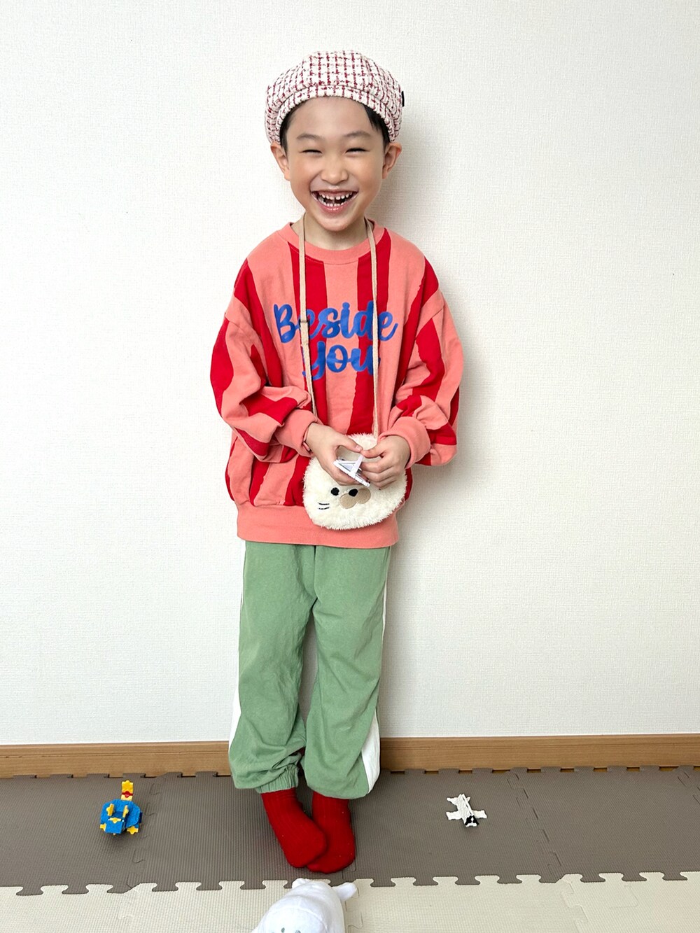 グリーン系のスウェットパンツ、ピンク系のスウェット、ホワイト系のショルダーバッグを着用したキッズの冬コーディネートの4枚目の写真