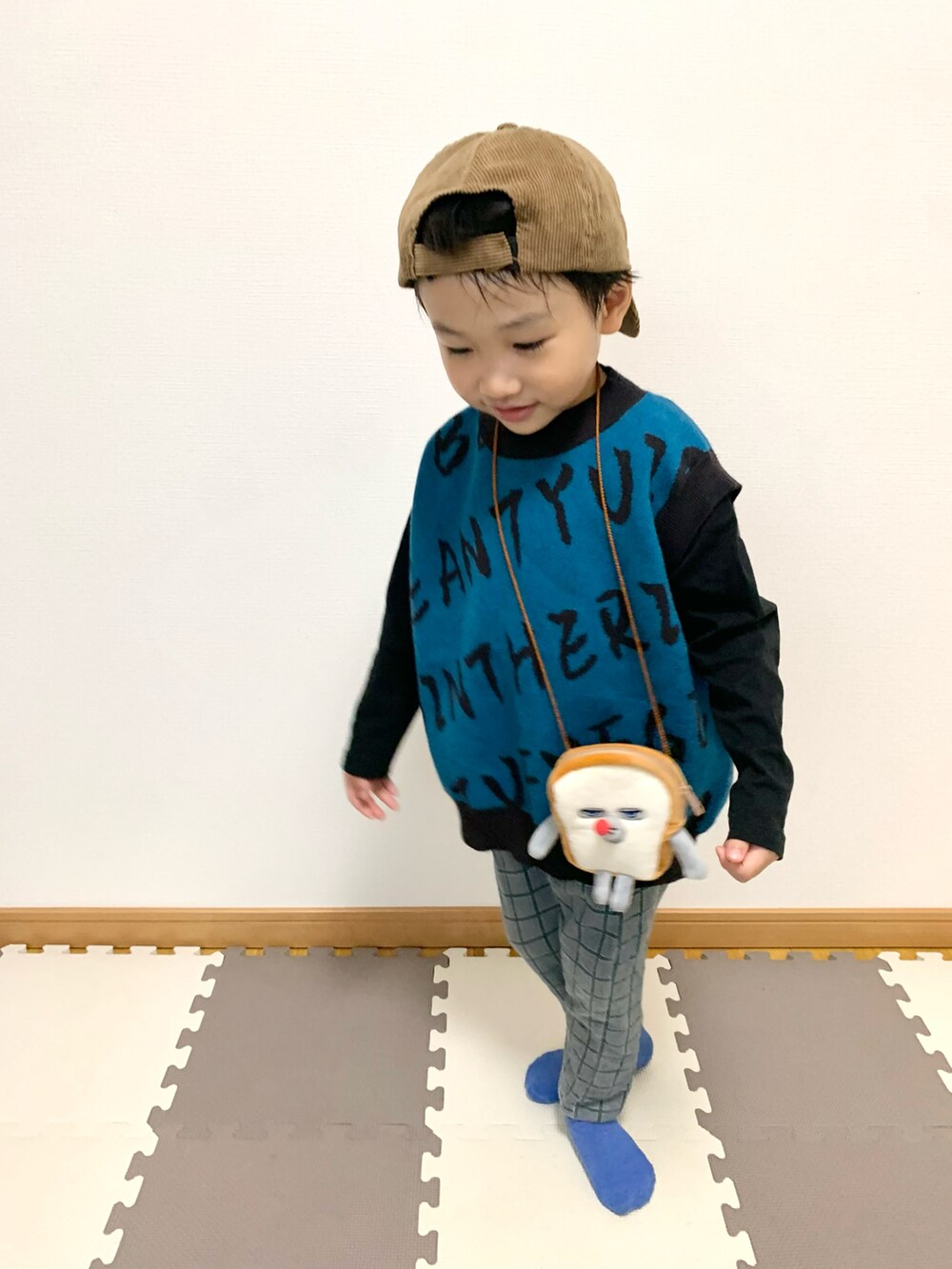 ブルー系のベスト、ブラウン系のショルダーバッグ、グレー系のスウェットパンツを着用したキッズの秋コーディネートの5枚目の写真