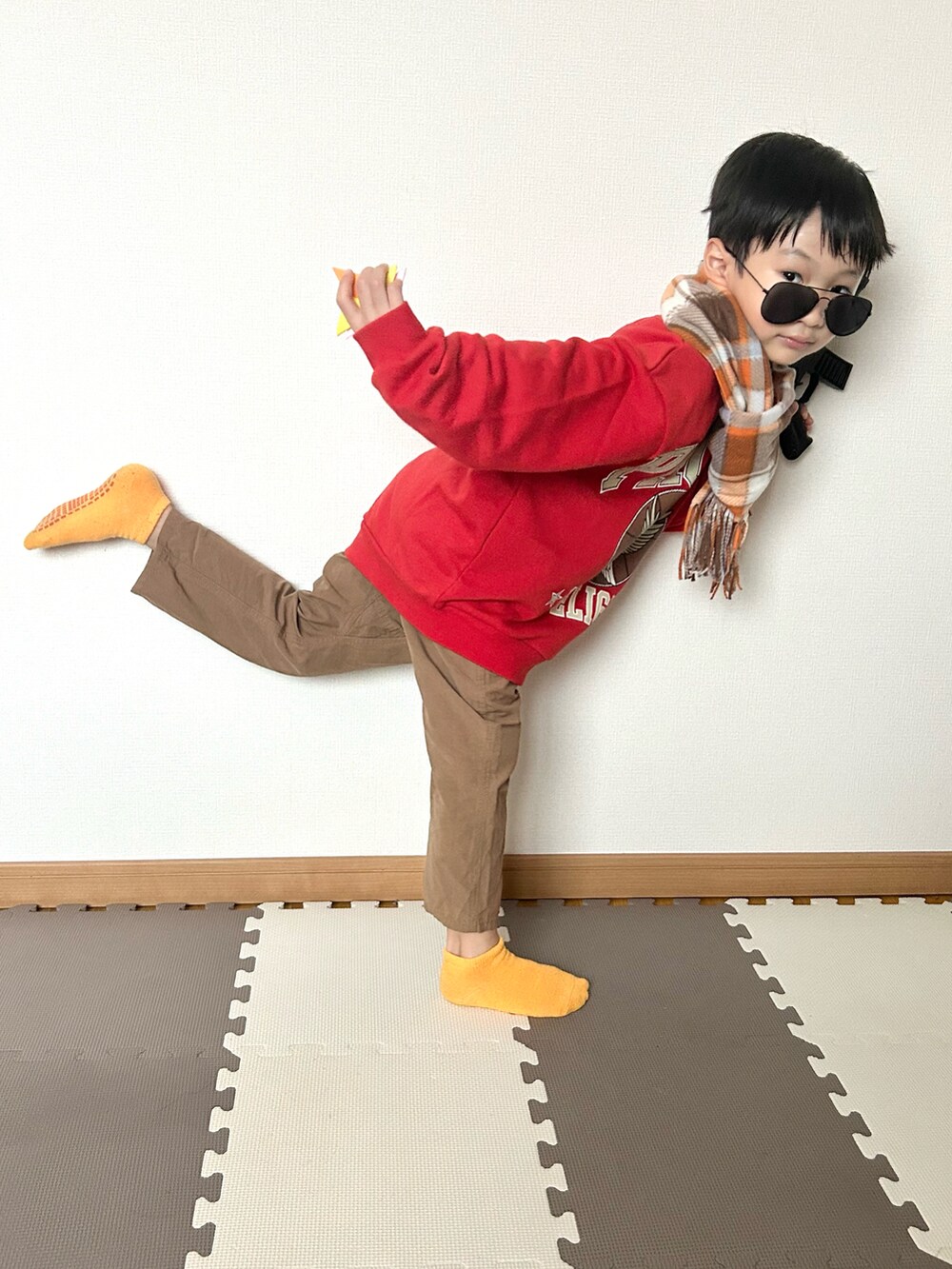 レッド系のスウェット、ブラウン系のパンツ、シルバー系のマフラーを着用したキッズの秋コーディネートの5枚目の写真