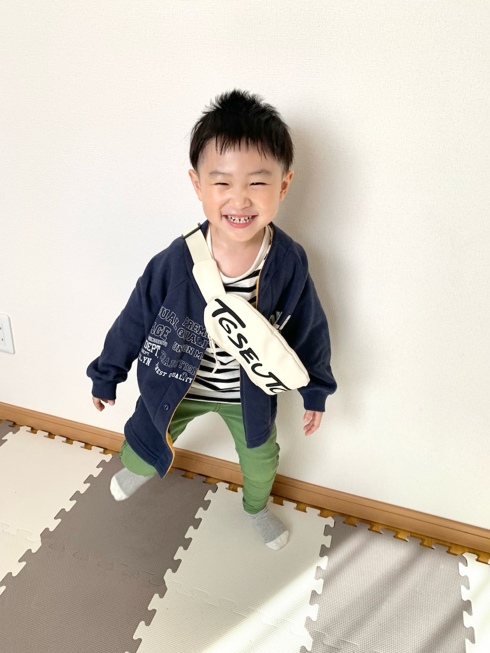ベージュ系のボディバッグ/ウエストポーチ、ブルー系のカーディガン/ボレロ、グリーン系のその他パンツを着用したキッズの春コーディネートの3枚目の写真