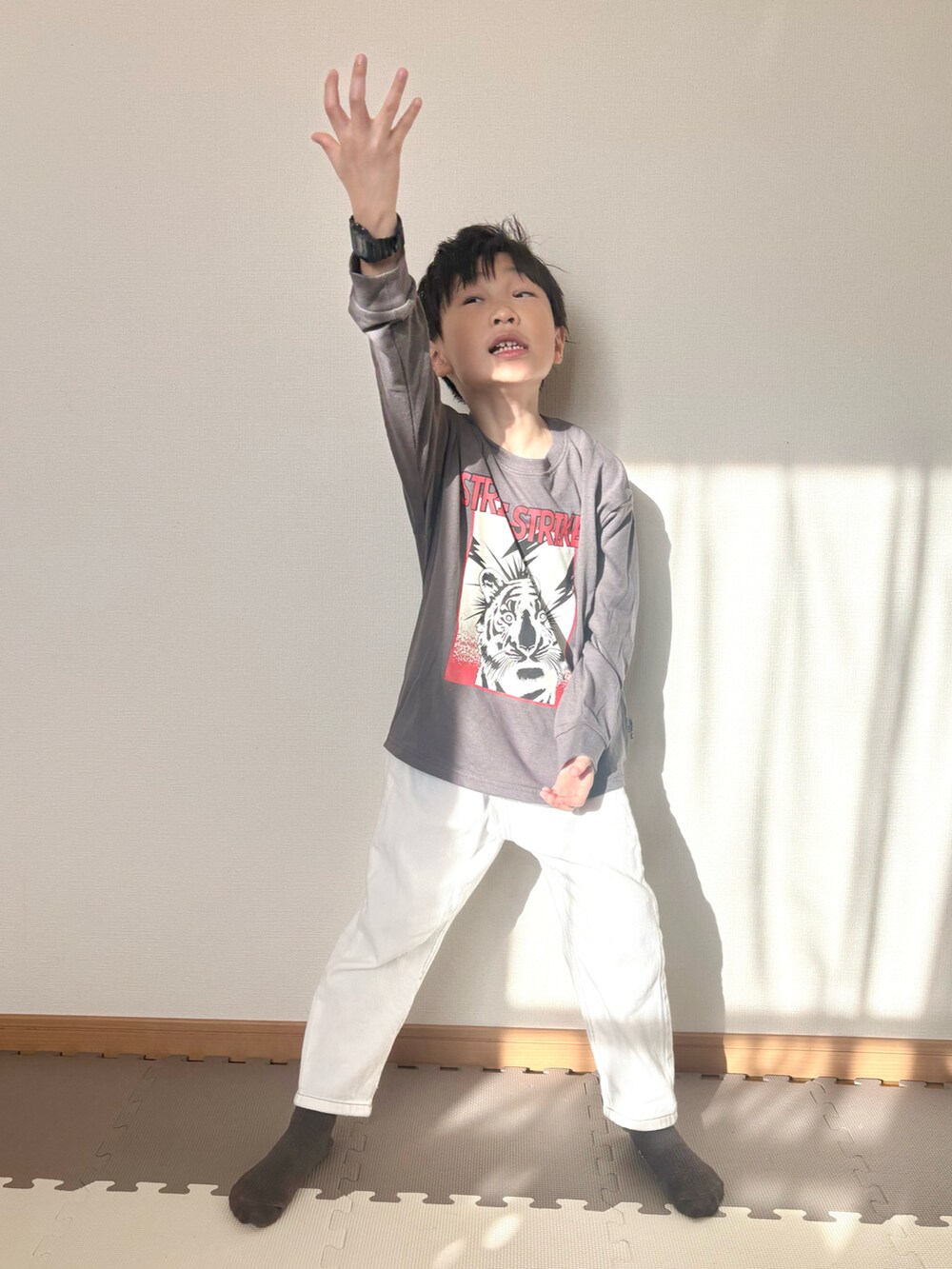 グレー系のTシャツ/カットソー、ホワイト系のデニムパンツ、ブラック系の腕時計を着用したキッズの春コーディネートの4枚目の写真