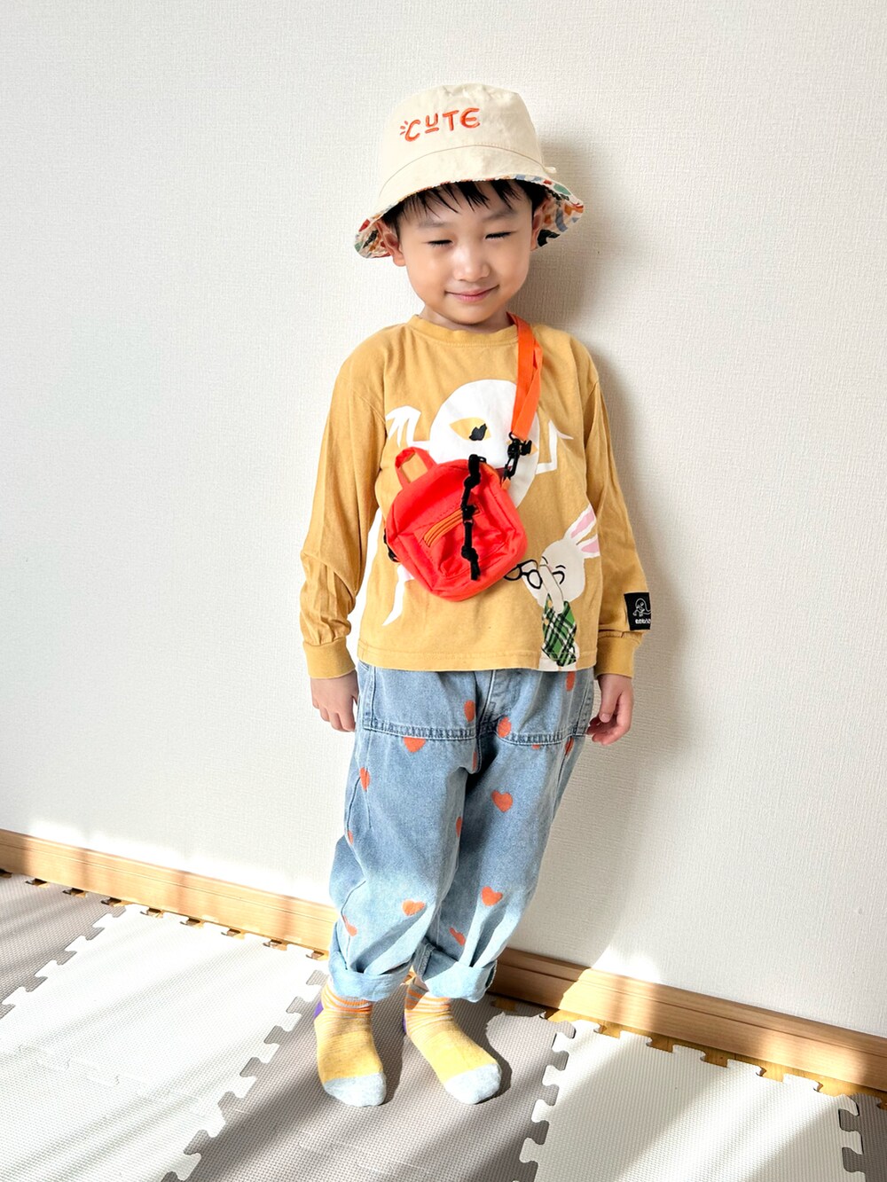 イエロー系のTシャツ/カットソー、ブルー系のデニムパンツ、オレンジ系のショルダーバッグを着用したキッズの春コーディネートの3枚目の写真