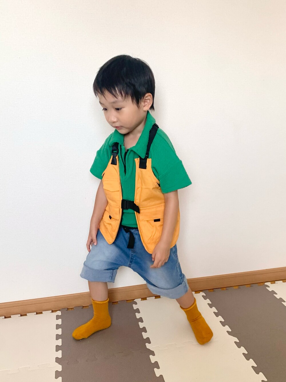 グリーン系のパンツ、オレンジ系のベスト、ブルー系のデニムパンツを着用したキッズの秋コーディネートの4枚目の写真