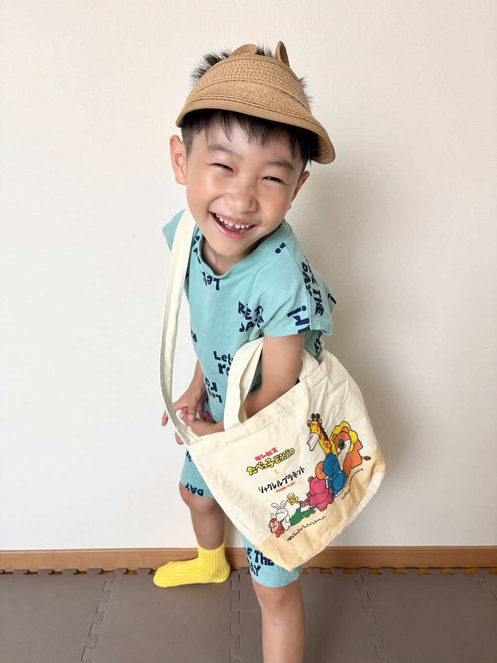 グリーン系のセットアップ、ベージュ系のトートバッグ、レッド系のおもちゃを着用したキッズの夏コーディネートの5枚目の写真