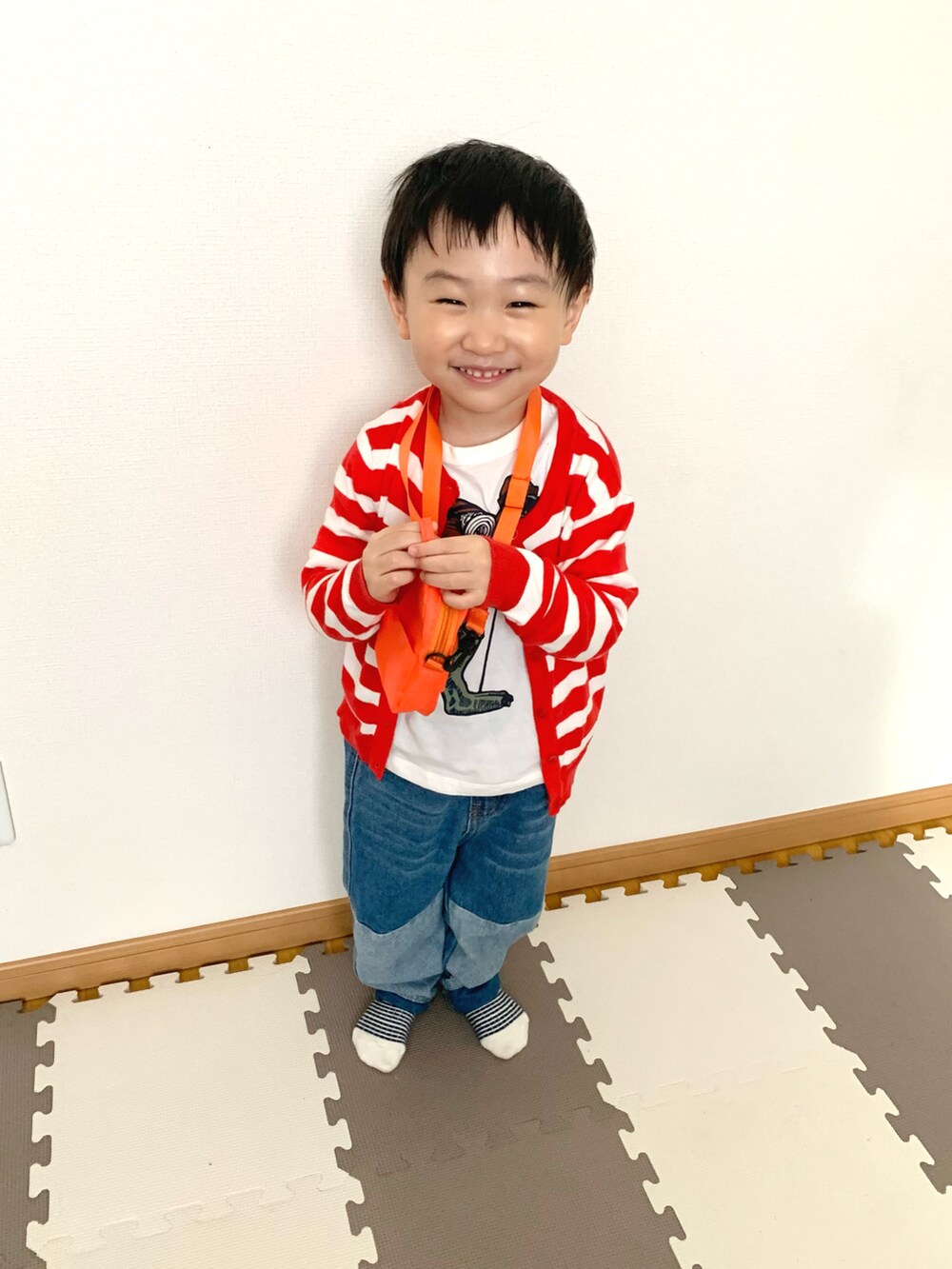ホワイト系のTシャツ/カットソー、ブルー系のデニムパンツ、レッド系のカーディガン/ボレロを着用したキッズの春コーディネートの2枚目の写真