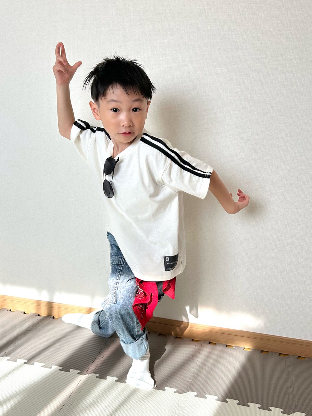 ホワイト系のTシャツ/カットソー、ブルー系のパンツ、レッド系のストール/ショールを着用したキッズの春コーディネートの4枚目の写真