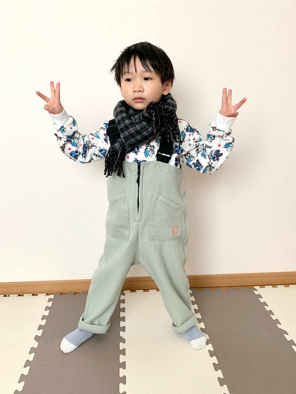 グリーン系のサロペット/オーバーオール、ホワイト系のスウェット、グレー系のマフラーを着用したキッズの秋コーディネートの3枚目の写真
