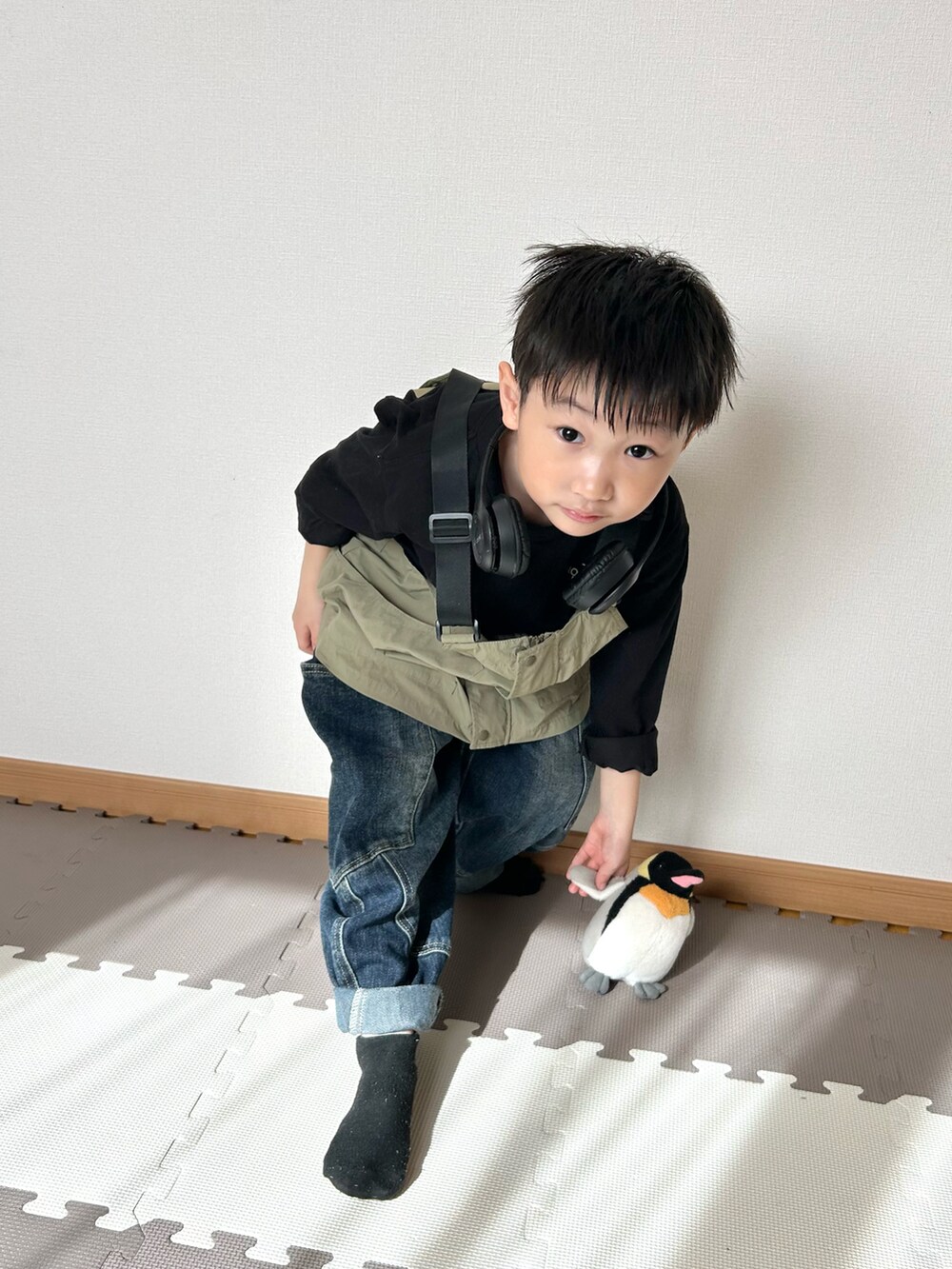 グリーン系のダウンベスト、ブラック系のTシャツ/カットソー、ブラック系のヘッドフォン/イヤホンを着用したキッズの春コーディネートの4枚目の写真