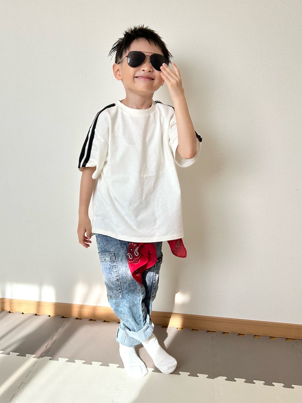 ホワイト系のTシャツ/カットソー、ブルー系のパンツ、レッド系のストール/ショールを着用したキッズの春コーディネートの2枚目の写真
