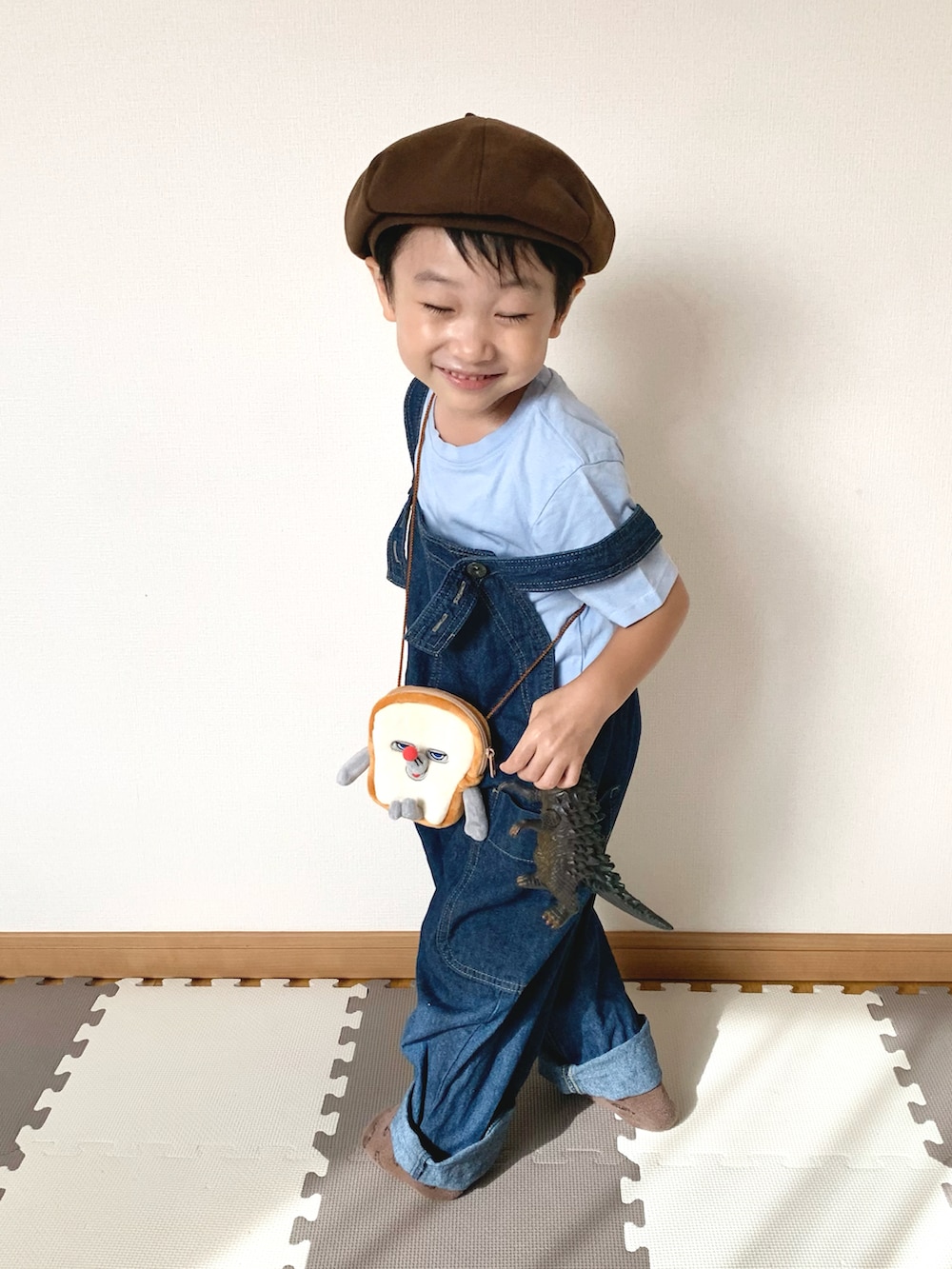 ブルー系のサロペット/オーバーオール、ブラウン系のショルダーバッグ、ブルー系のTシャツ/カットソーを着用したキッズの秋コーディネートの3枚目の写真