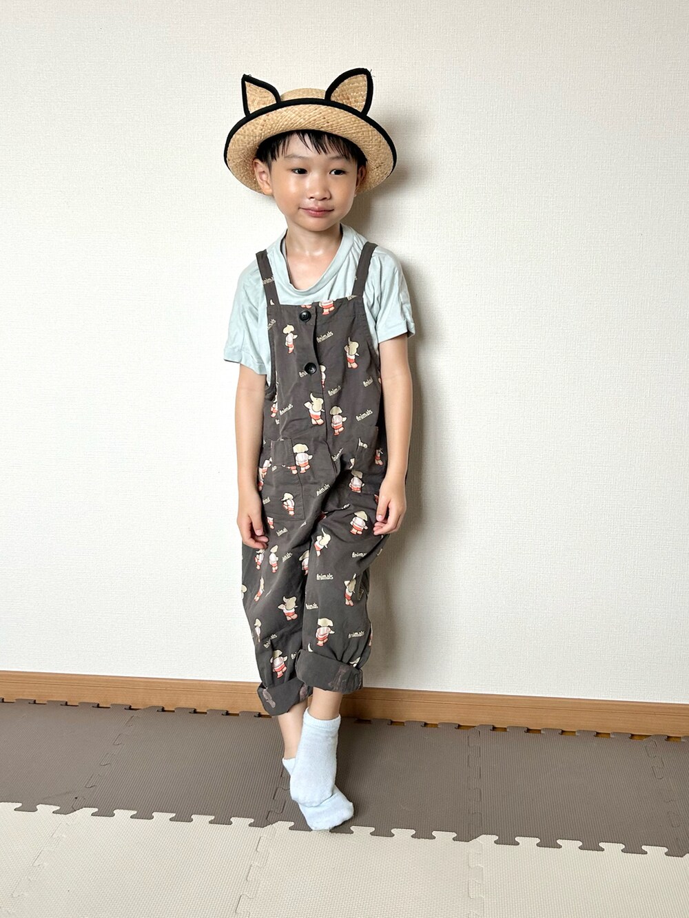 グレー系のサロペット/オーバーオール、グリーン系のTシャツ/カットソー、ベージュ系のハットを着用したキッズの夏コーディネートの3枚目の写真