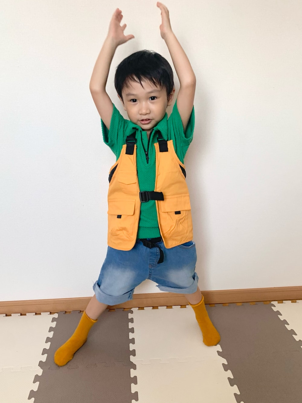 グリーン系のパンツ、オレンジ系のベスト、ブルー系のデニムパンツを着用したキッズの秋コーディネートの2枚目の写真