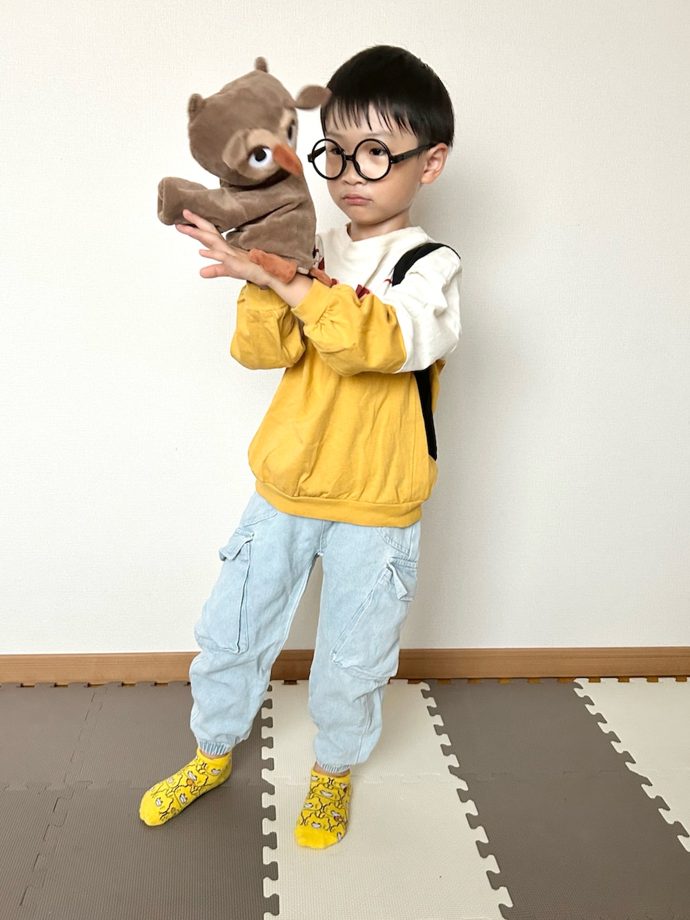 イエロー系のTシャツ/カットソー、ブルー系のデニムパンツ、ブラック系のバックパック/リュックを着用したキッズの秋コーディネートの3枚目の写真