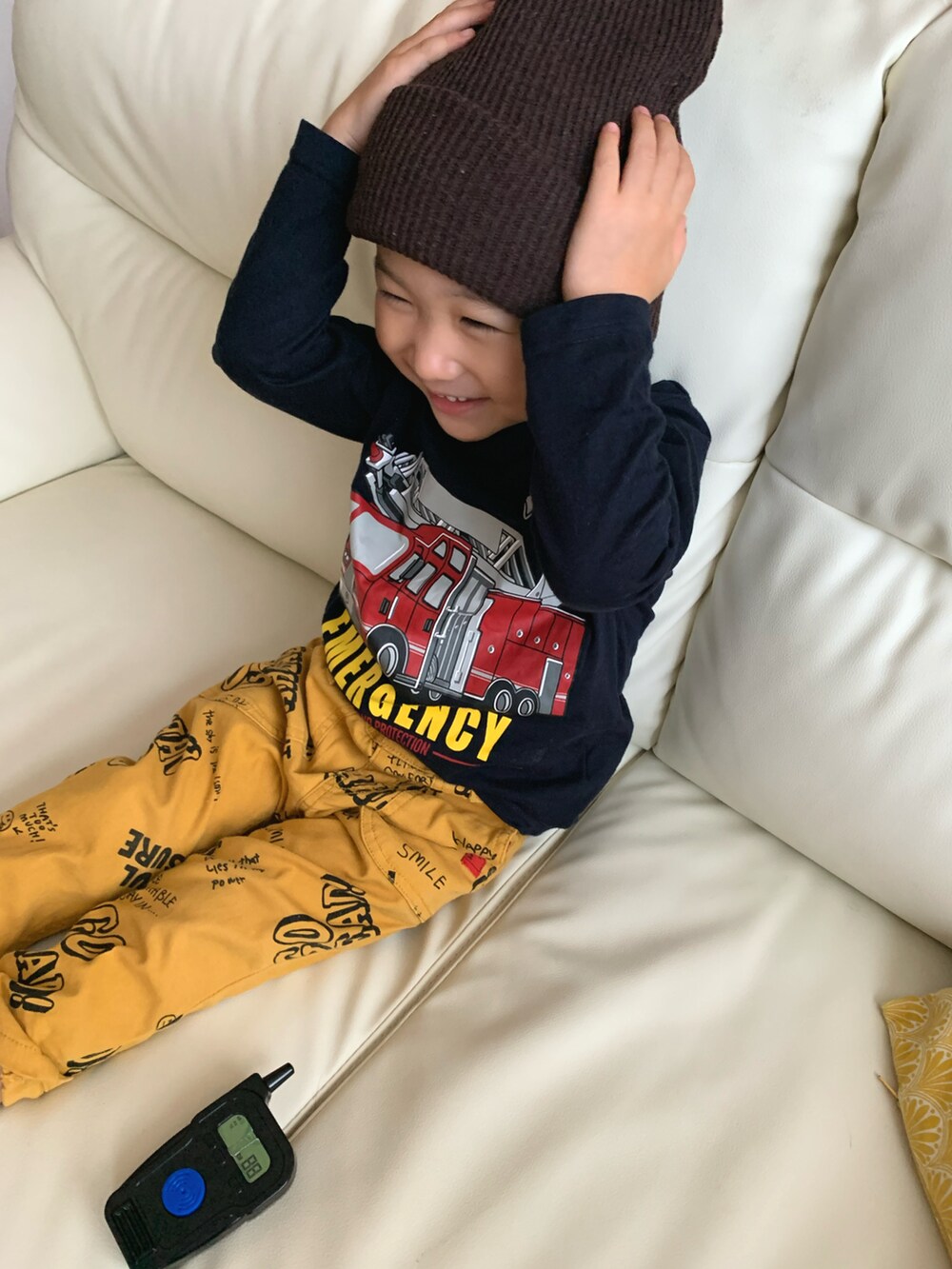 ブルー系のTシャツ/カットソー、イエロー系のチノパンツ、ブラウン系のニットキャップ/ビーニーを着用したキッズの秋コーディネートの2枚目の写真