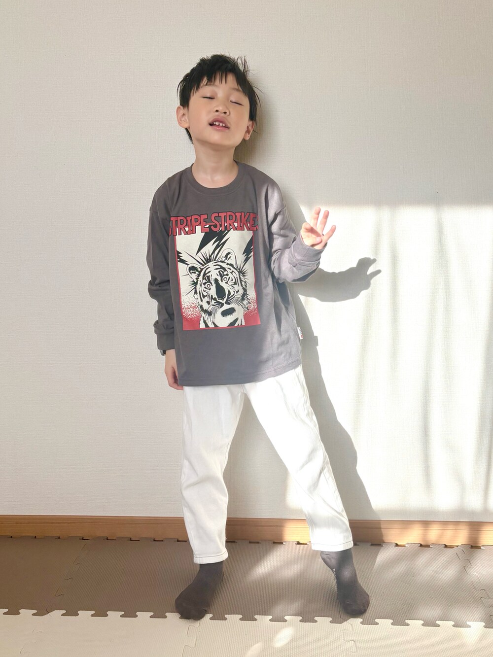 グレー系のTシャツ/カットソー、ホワイト系のデニムパンツ、ブラック系の腕時計を着用したキッズの春コーディネートの3枚目の写真