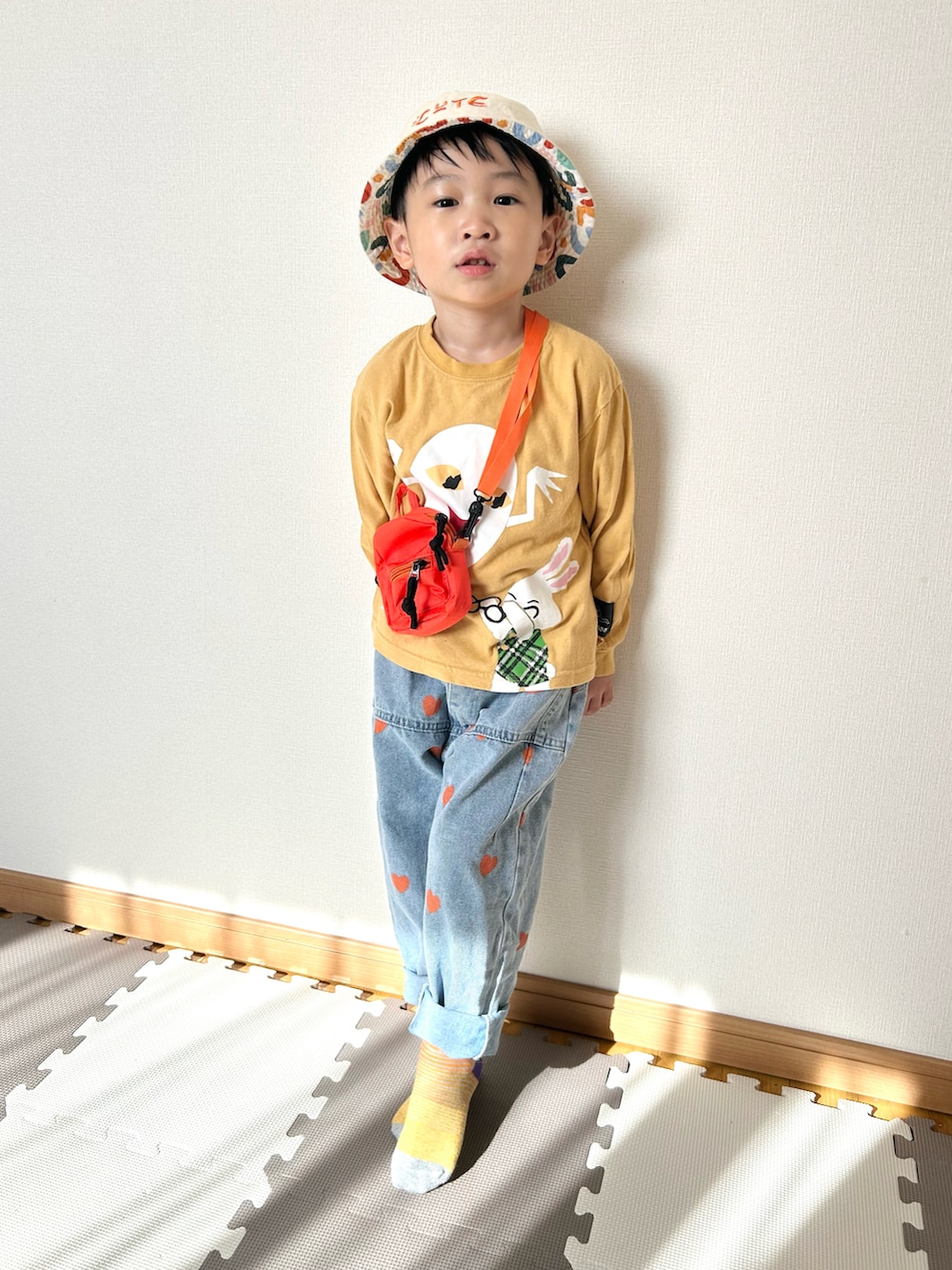 イエロー系のTシャツ/カットソー、ブルー系のデニムパンツ、オレンジ系のショルダーバッグを着用したキッズの春コーディネートの4枚目の写真
