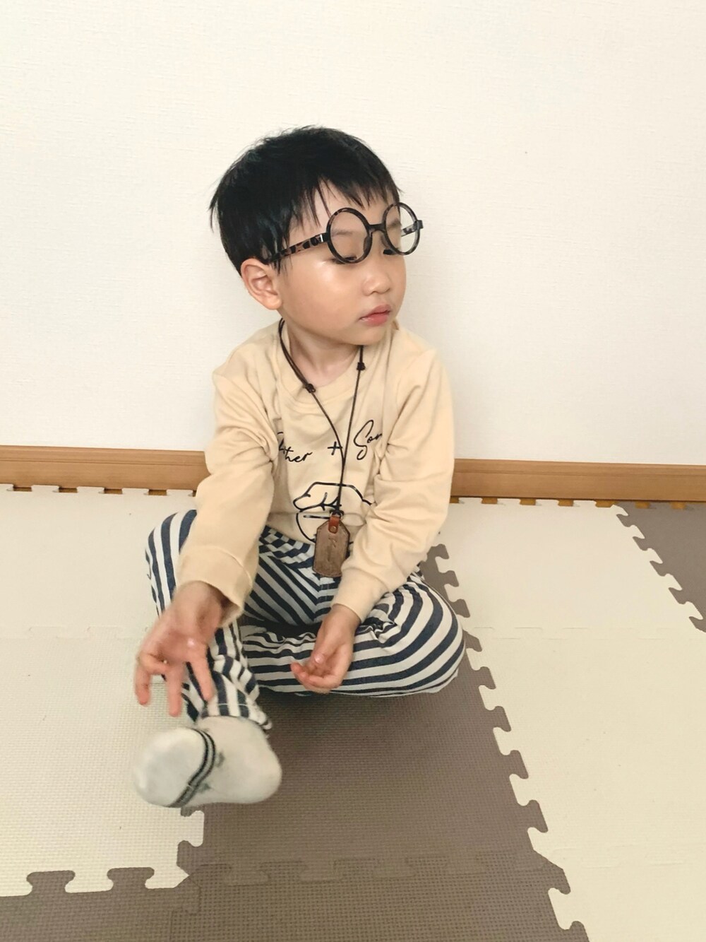 ベージュ系のスウェット、ブルー系のチノパンツ、ブラウン系のネックレスを着用したキッズの春コーディネートの3枚目の写真