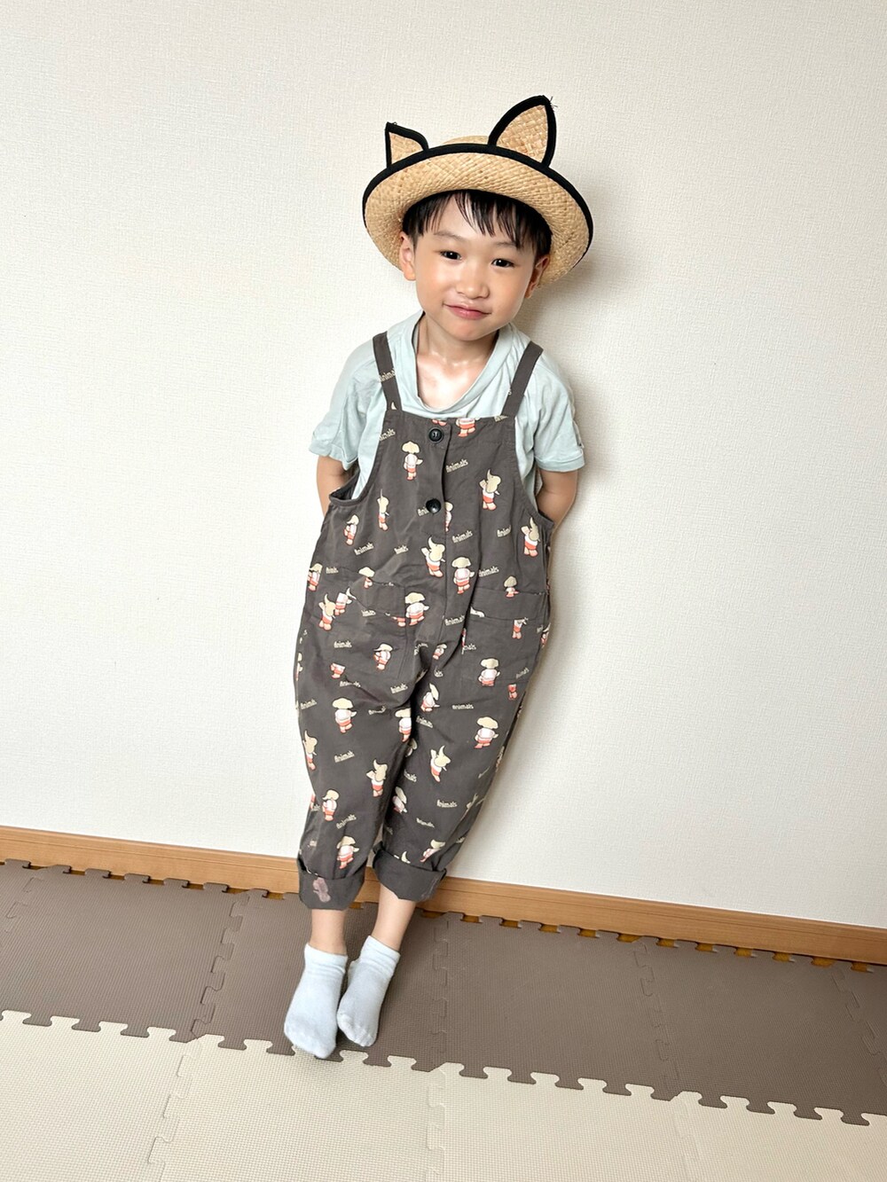 グレー系のサロペット/オーバーオール、グリーン系のTシャツ/カットソー、ベージュ系のハットを着用したキッズの夏コーディネートの4枚目の写真