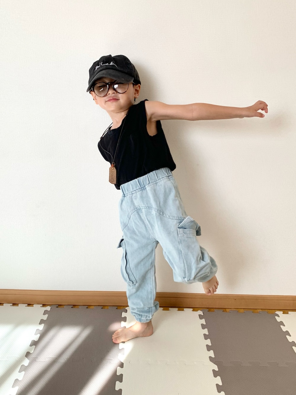 ブルー系のデニムパンツ、ブラック系のタンクトップ、ブラック系のキャップを着用したキッズの夏コーディネートの3枚目の写真