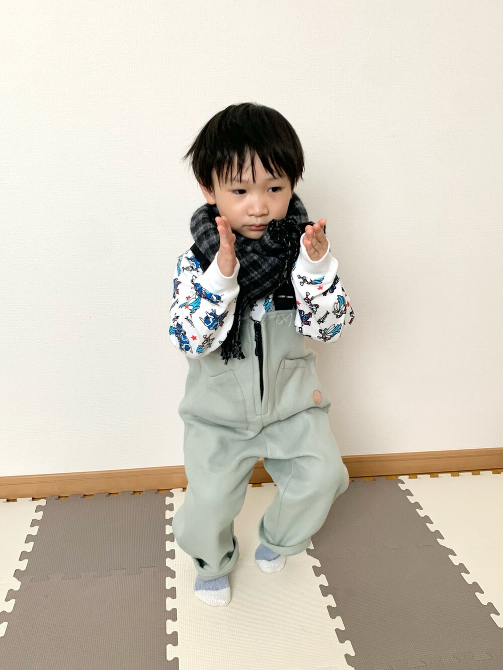 グリーン系のサロペット/オーバーオール、ホワイト系のスウェット、グレー系のマフラーを着用したキッズの秋コーディネートの5枚目の写真