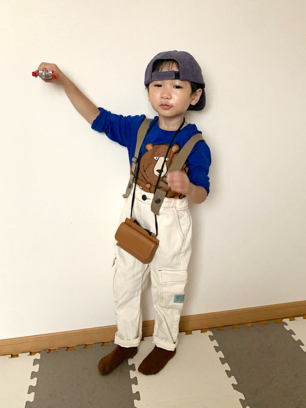 ホワイト系のサロペット/オーバーオール、グリーン系のTシャツ/カットソー、ブラウン系のショルダーバッグを着用したキッズの秋コーディネートの3枚目の写真