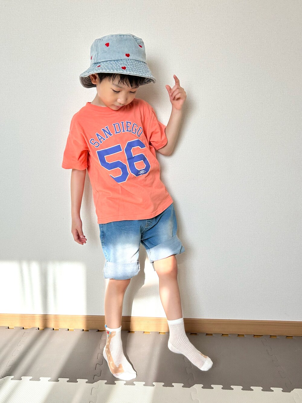 ブルー系のデニムパンツ、オレンジ系のTシャツ/カットソー、ブルー系のハットを着用したキッズの春コーディネートの2枚目の写真