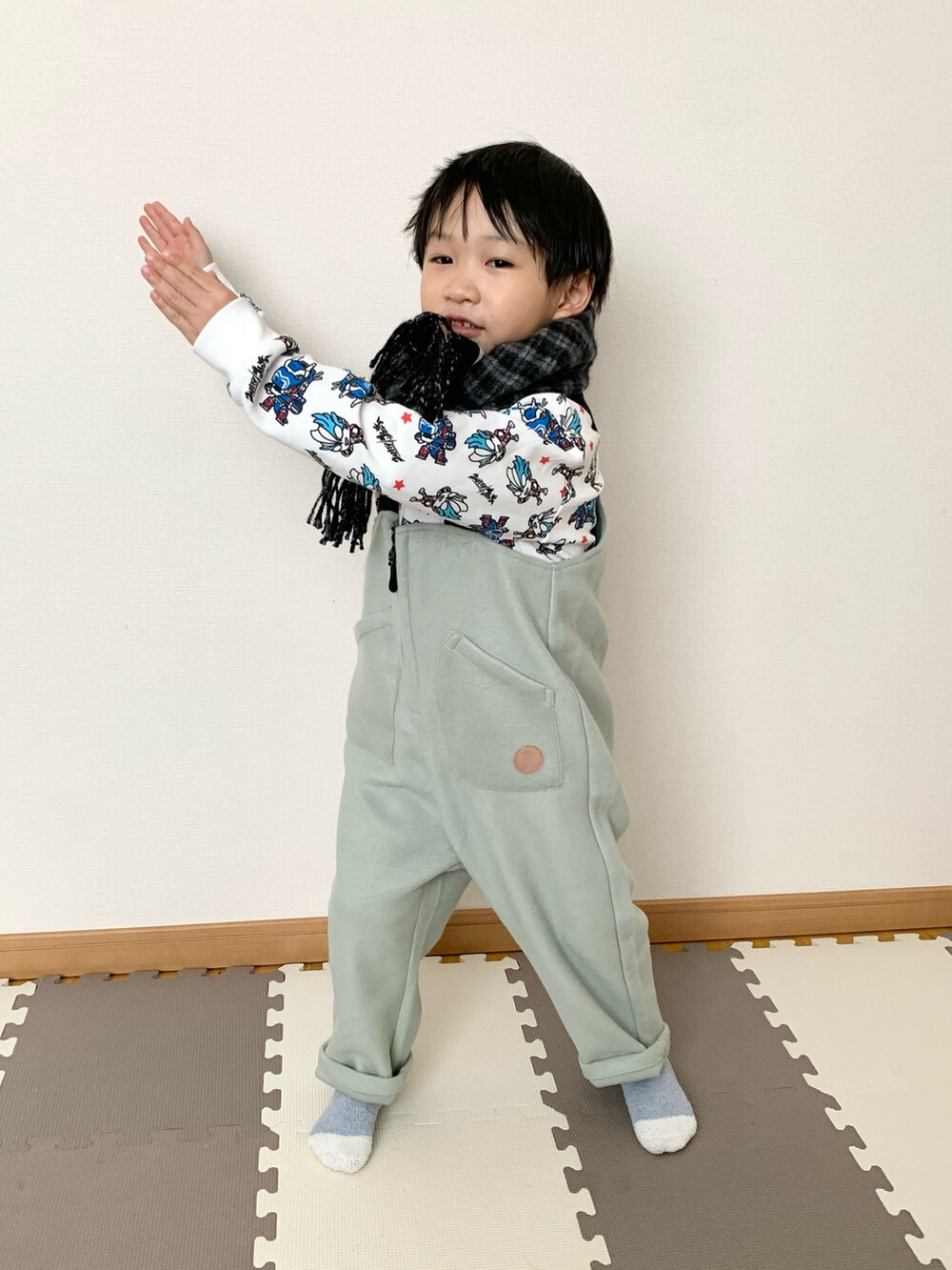 グリーン系のサロペット/オーバーオール、ホワイト系のスウェット、グレー系のマフラーを着用したキッズの秋コーディネートの2枚目の写真