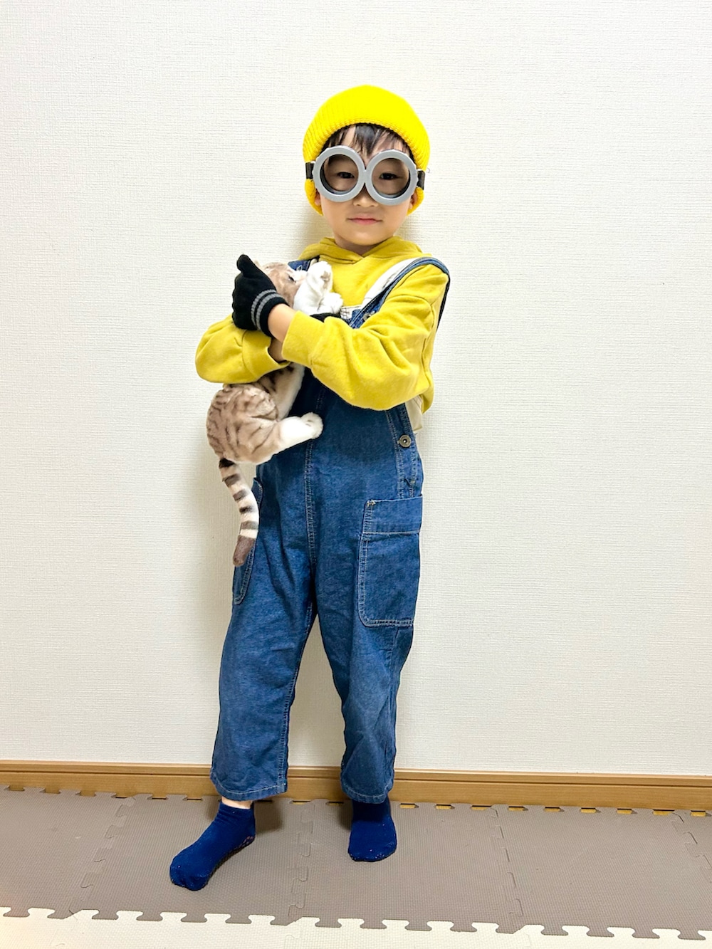 イエロー系のパーカー、ブルー系のサロペット/オーバーオール、グレー系のメガネを着用したキッズの秋コーディネートの2枚目の写真