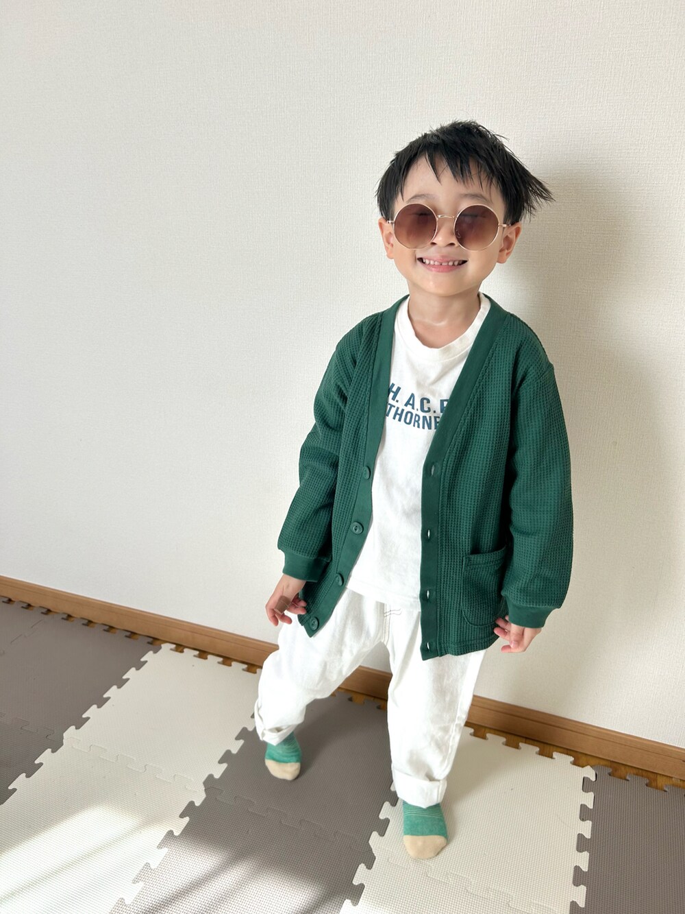 ホワイト系のデニムパンツ、ホワイト系のTシャツ/カットソー、グリーン系のカーディガン/ボレロを着用したキッズの春コーディネートの3枚目の写真