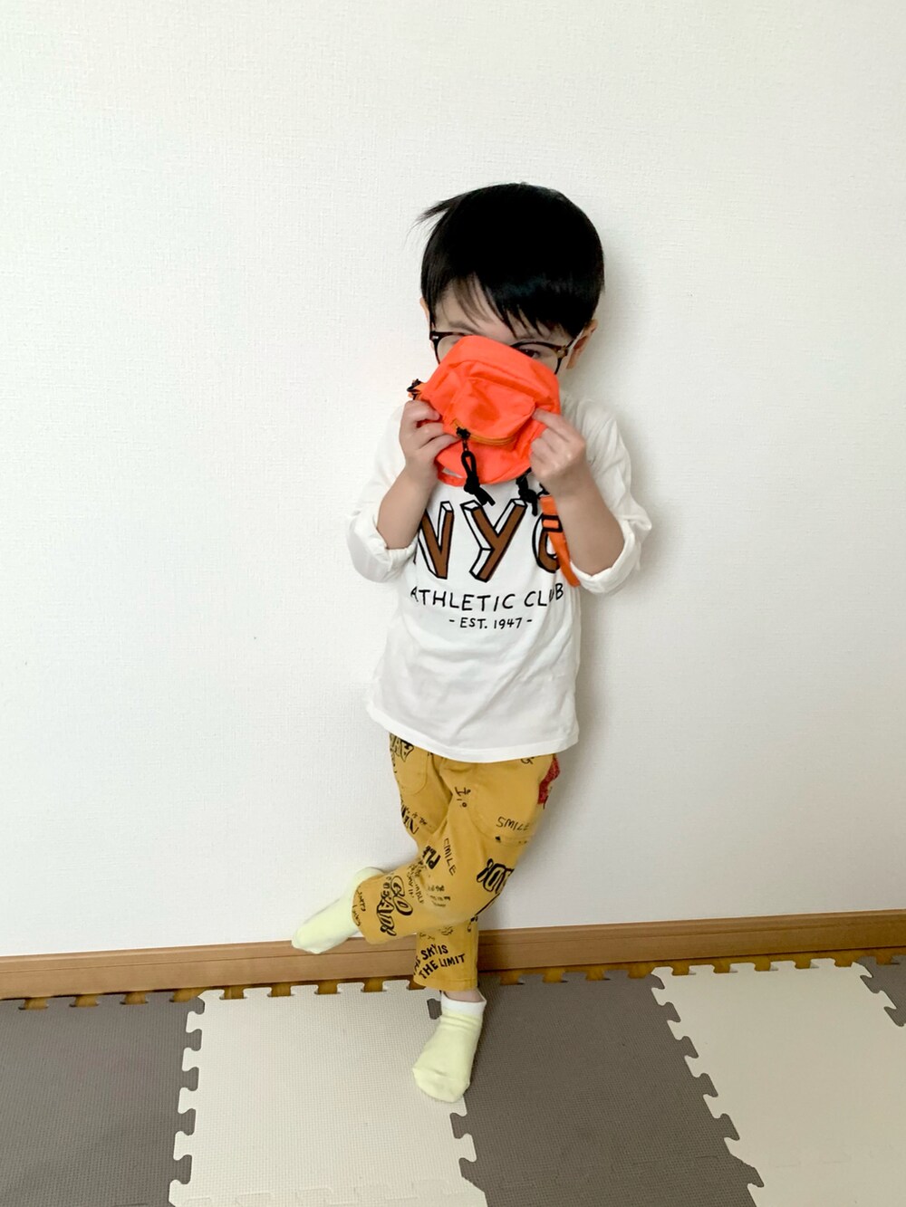 オレンジ系のショルダーバッグ、イエロー系のその他パンツ、ホワイト系のTシャツ/カットソーを着用したキッズの春コーディネートの4枚目の写真