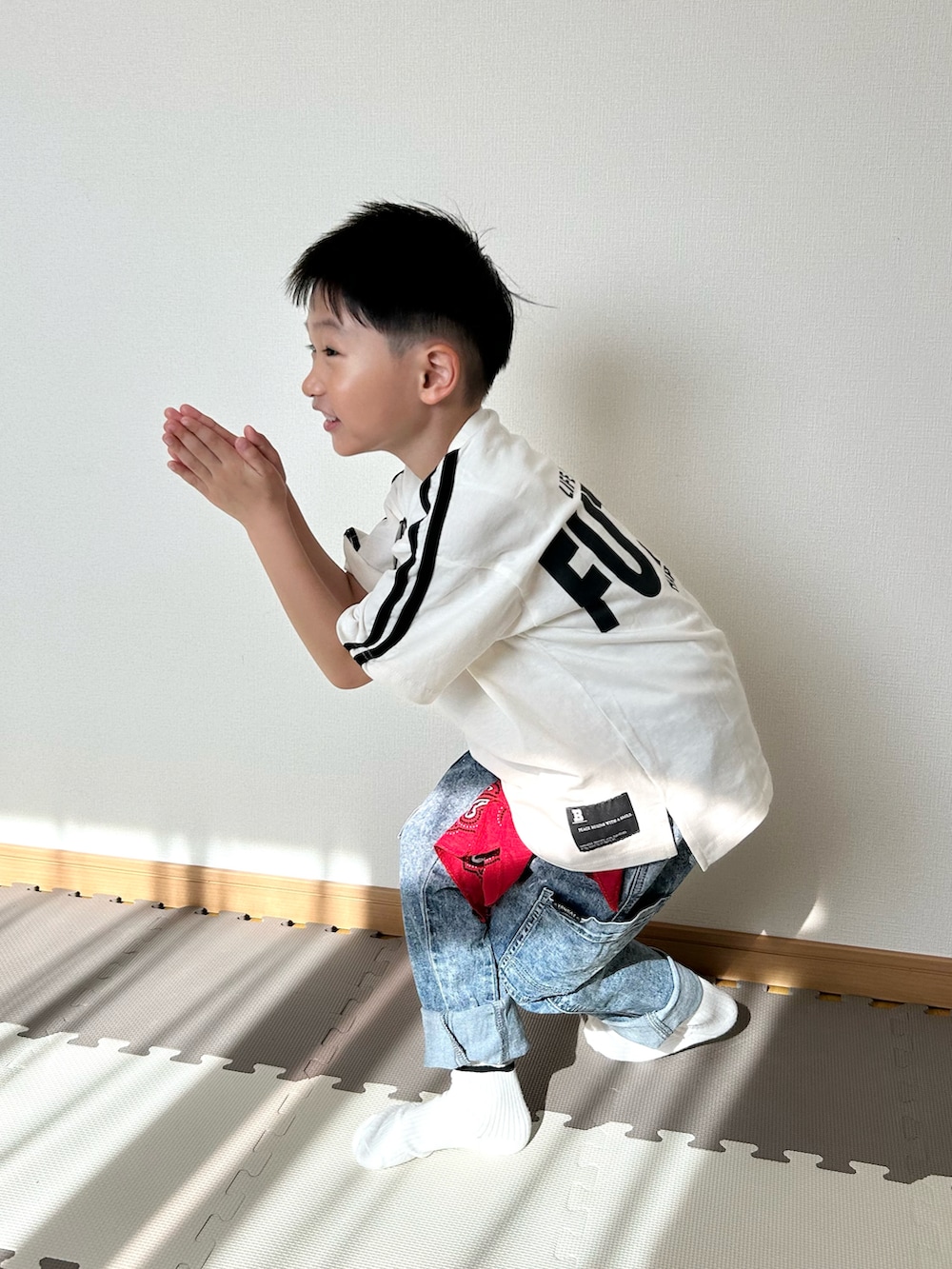ホワイト系のTシャツ/カットソー、ブルー系のパンツ、レッド系のストール/ショールを着用したキッズの春コーディネートの3枚目の写真