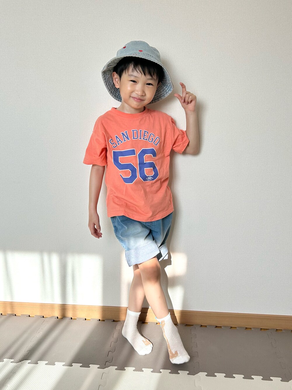 ブルー系のデニムパンツ、オレンジ系のTシャツ/カットソー、ブルー系のハットを着用したキッズの春コーディネートの3枚目の写真