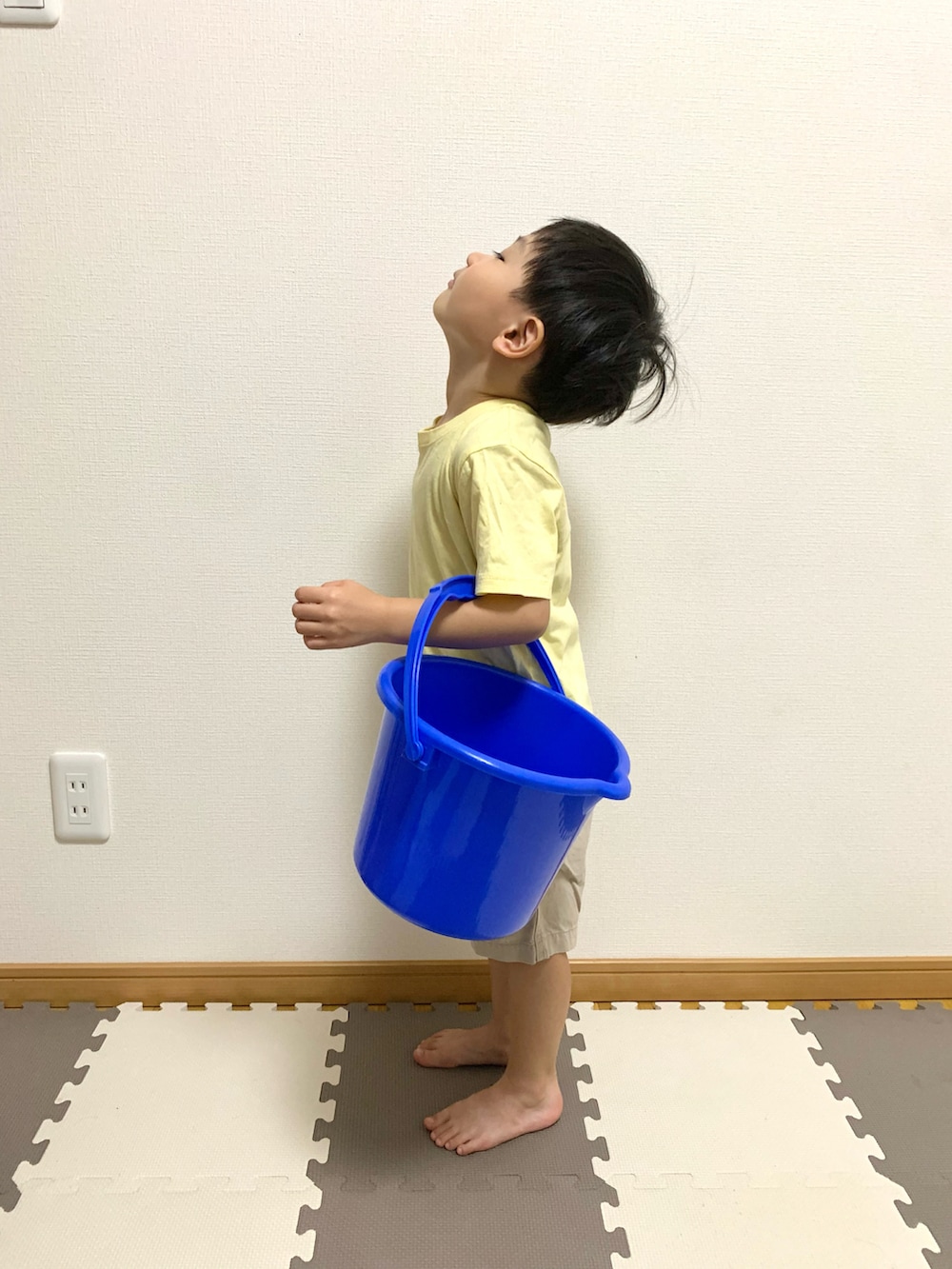 イエロー系のTシャツ/カットソー、ベージュ系のチノパンツ、ブルー系のランドリーグッズを着用したキッズの秋コーディネートの2枚目の写真