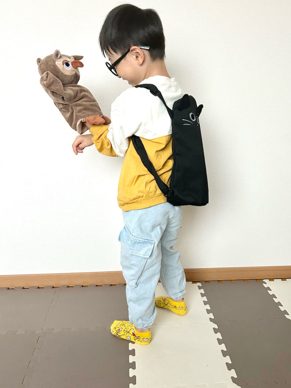 イエロー系のTシャツ/カットソー、ブルー系のデニムパンツ、ブラック系のバックパック/リュックを着用したキッズの秋コーディネートの5枚目の写真