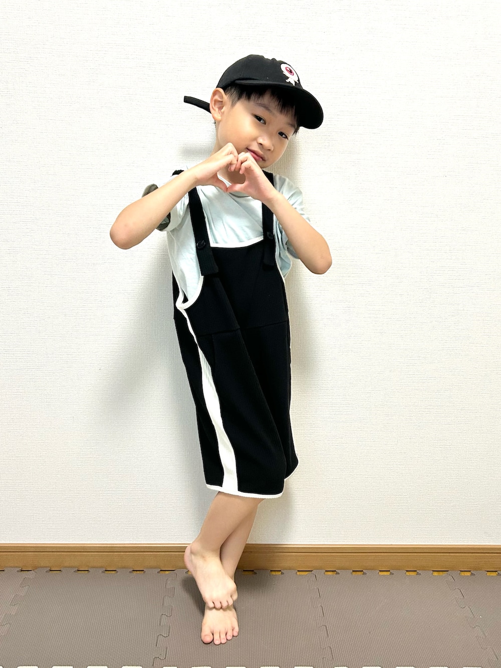グリーン系のTシャツ/カットソー、ブラック系のサロペット/オーバーオール、ホワイト系のキャップを着用したキッズの夏コーディネートの5枚目の写真