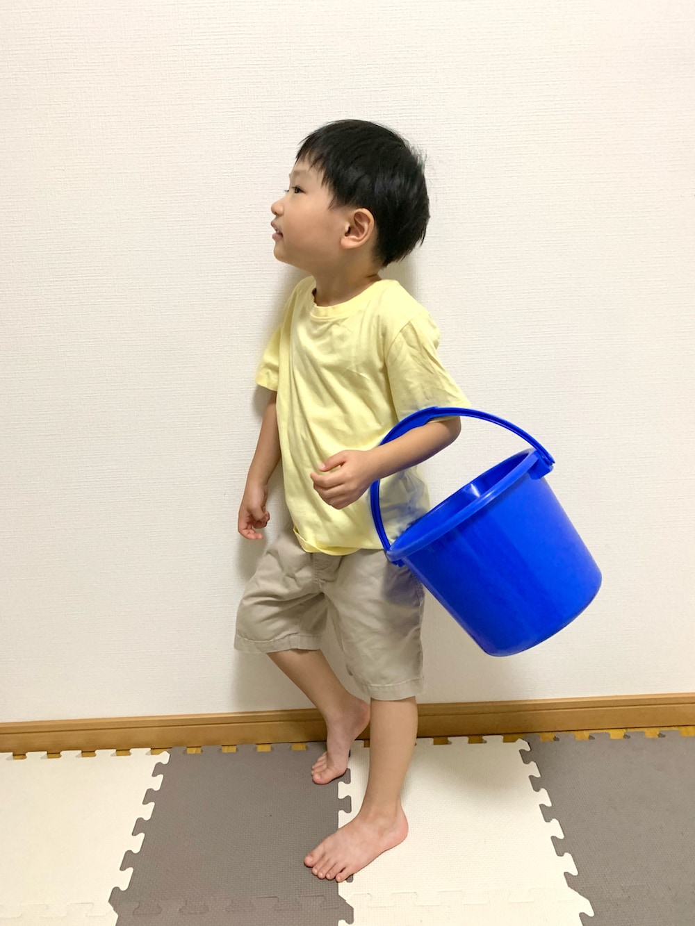 イエロー系のTシャツ/カットソー、ベージュ系のチノパンツ、ブルー系のランドリーグッズを着用したキッズの秋コーディネートの3枚目の写真