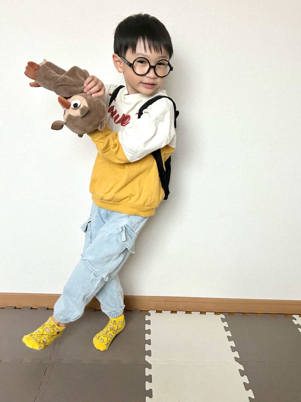 イエロー系のTシャツ/カットソー、ブルー系のデニムパンツ、ブラック系のバックパック/リュックを着用したキッズの秋コーディネートの2枚目の写真