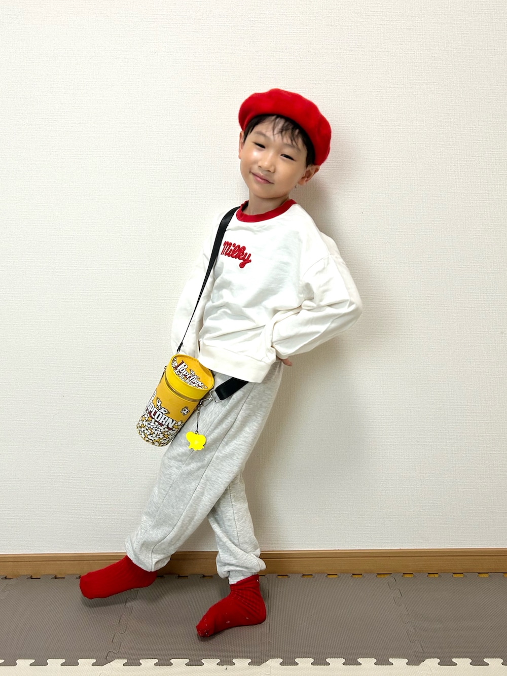 グレー系のスウェットパンツ、ホワイト系のスウェット、イエロー系のショルダーバッグを着用したキッズの秋コーディネートの3枚目の写真