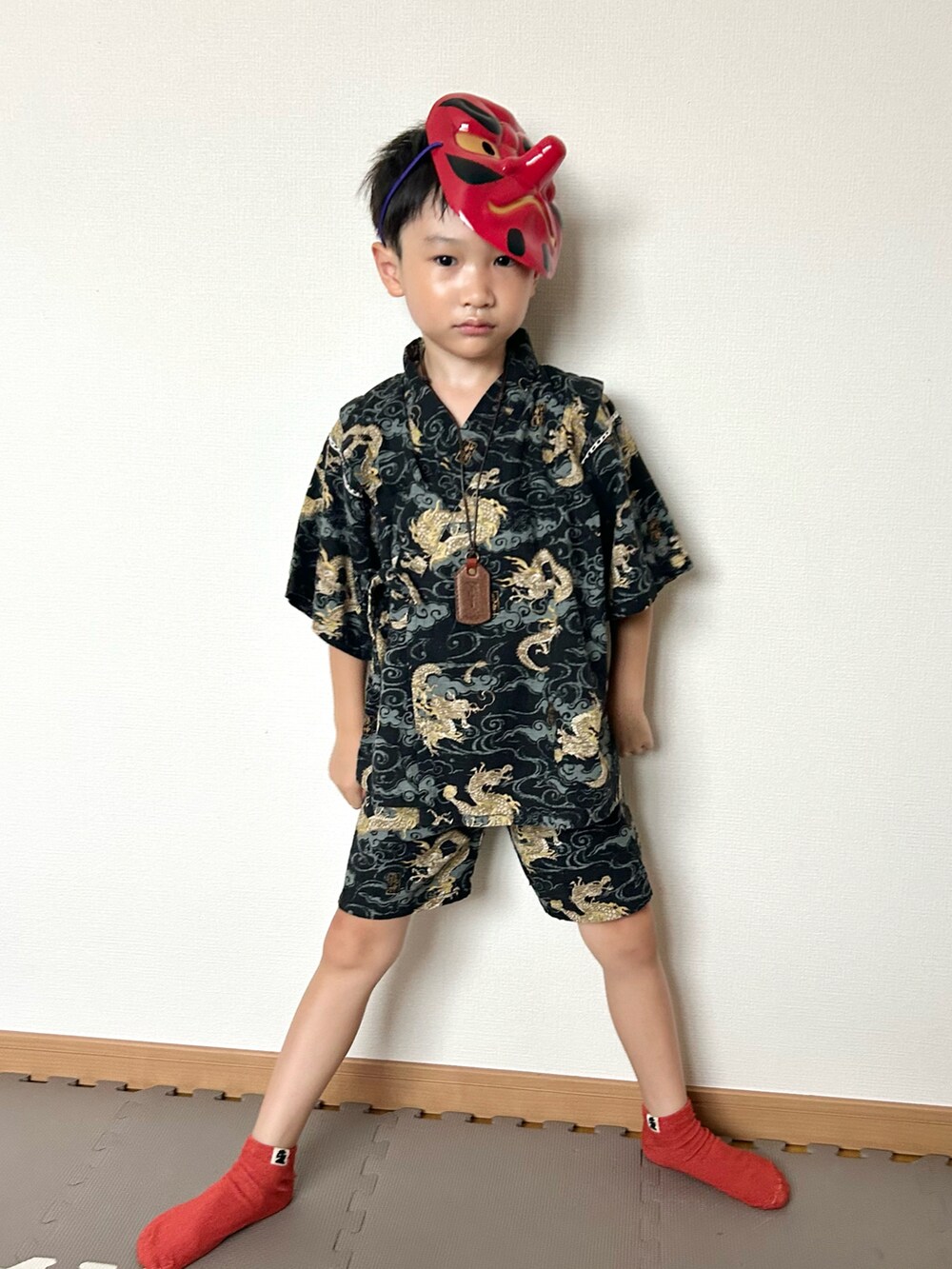 ブラウン系のネックレス、ブラック系の浴衣、レッド系の和装小物を着用したキッズの夏コーディネートの2枚目の写真