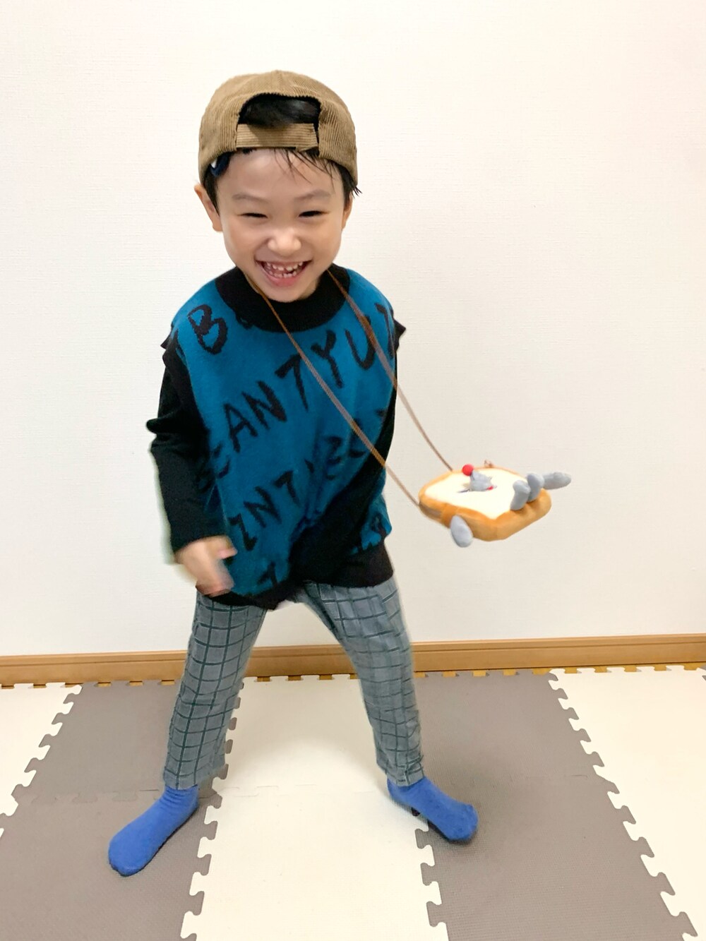 ブルー系のベスト、ブラウン系のショルダーバッグ、グレー系のスウェットパンツを着用したキッズの秋コーディネートの3枚目の写真