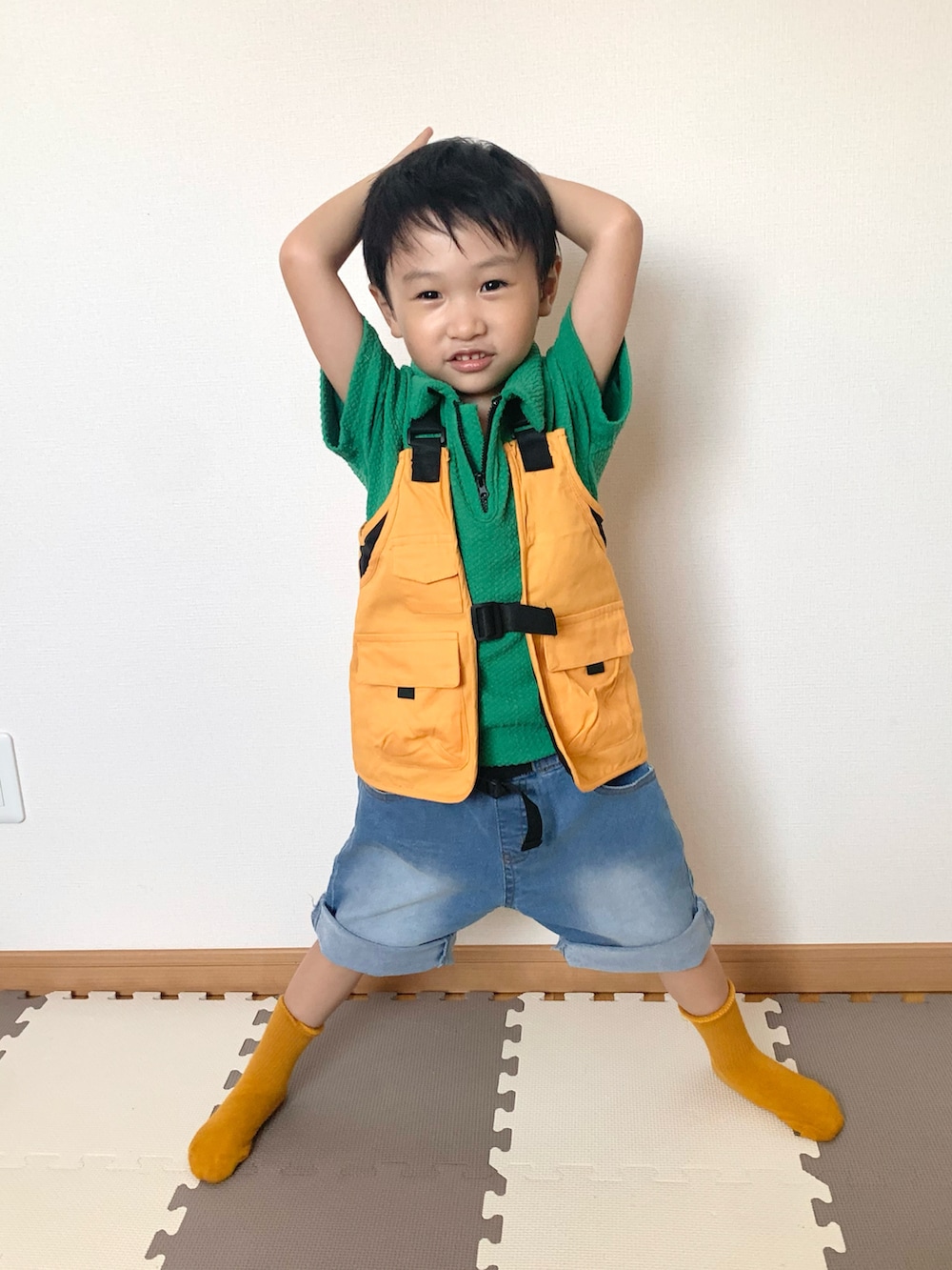 グリーン系のパンツ、オレンジ系のベスト、ブルー系のデニムパンツを着用したキッズの秋コーディネートの3枚目の写真