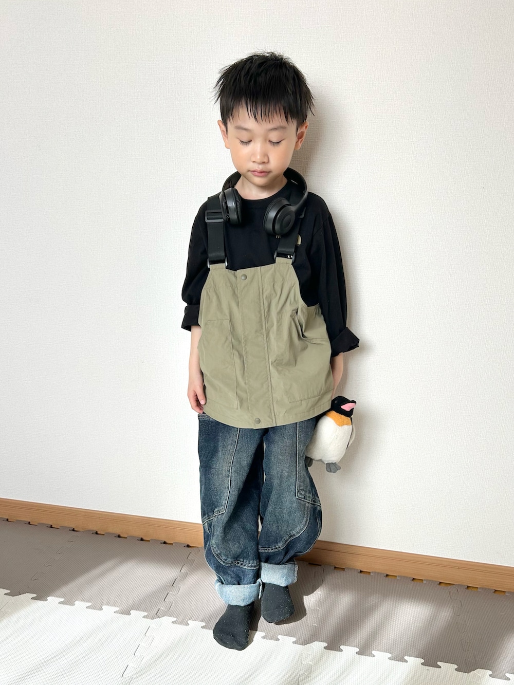 グリーン系のダウンベスト、ブラック系のTシャツ/カットソー、ブラック系のヘッドフォン/イヤホンを着用したキッズの春コーディネートの3枚目の写真