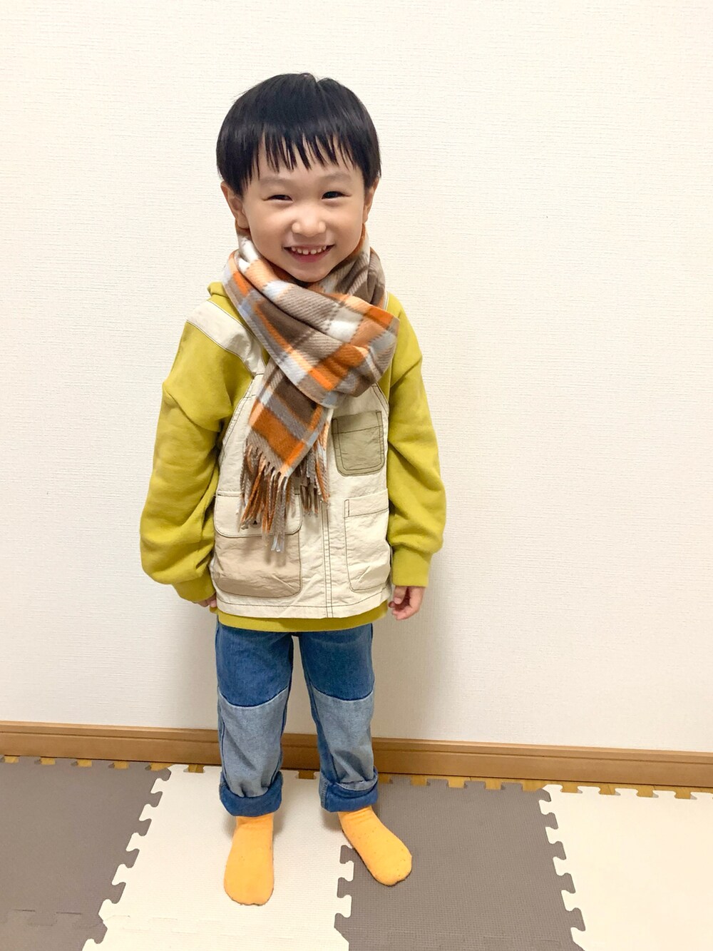 イエロー系のパーカー、ブルー系のデニムパンツ、その他のソックス/靴下を着用したキッズの秋コーディネートの2枚目の写真